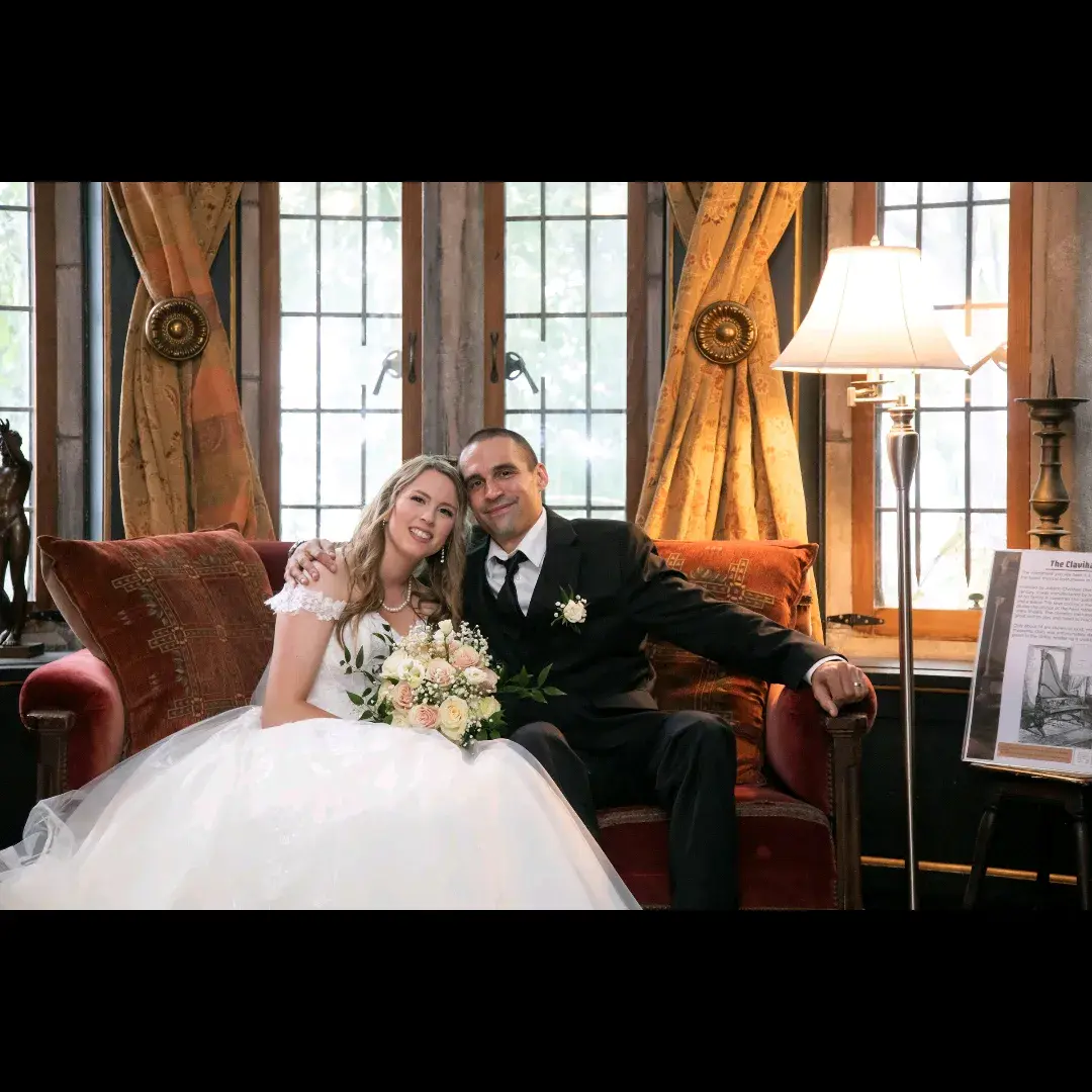 Bride wearing Harlem wedding dress by Maggie Sottero sitting on a couch with her husband