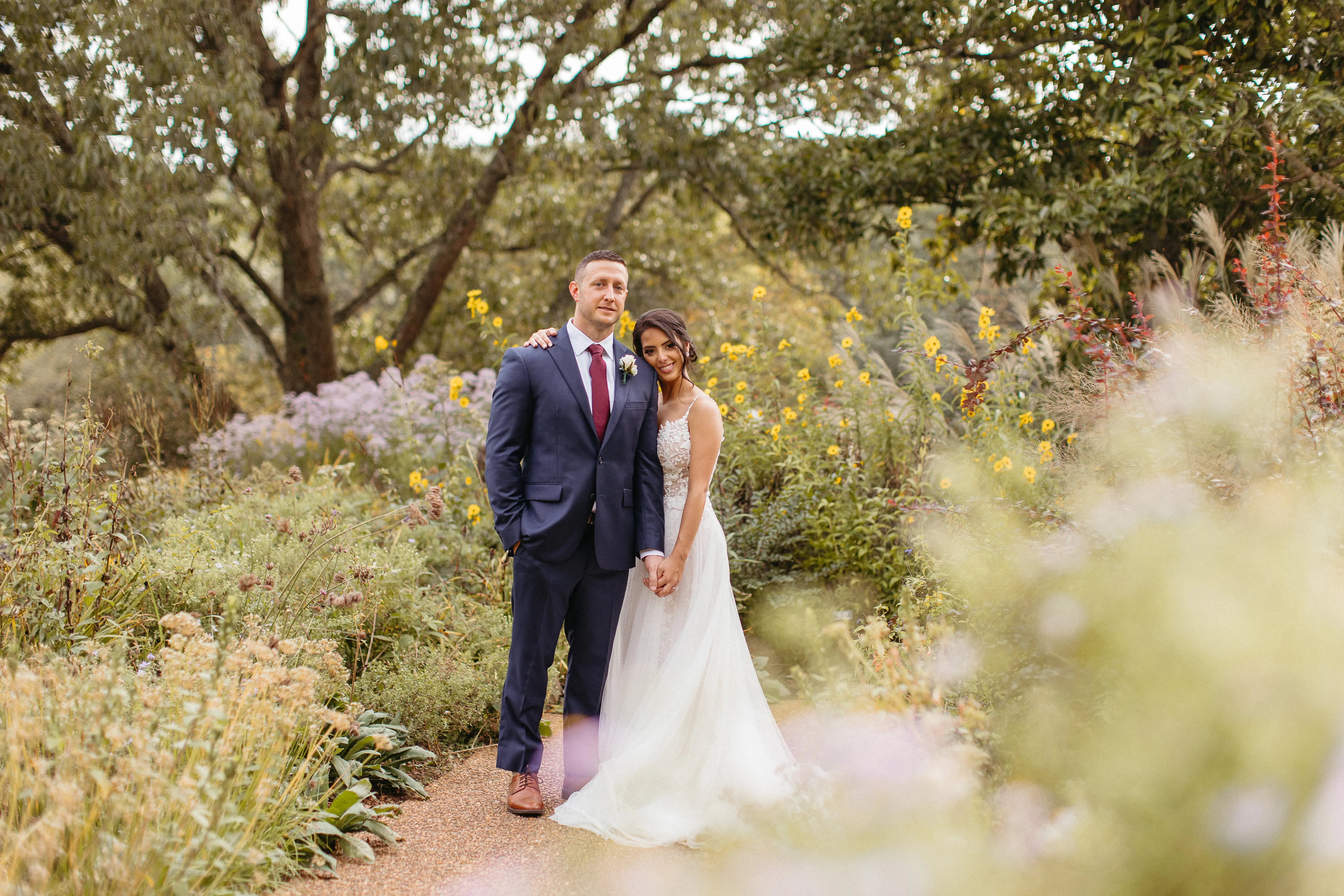 Bride leaning on her groom surrounded by wild flowers.