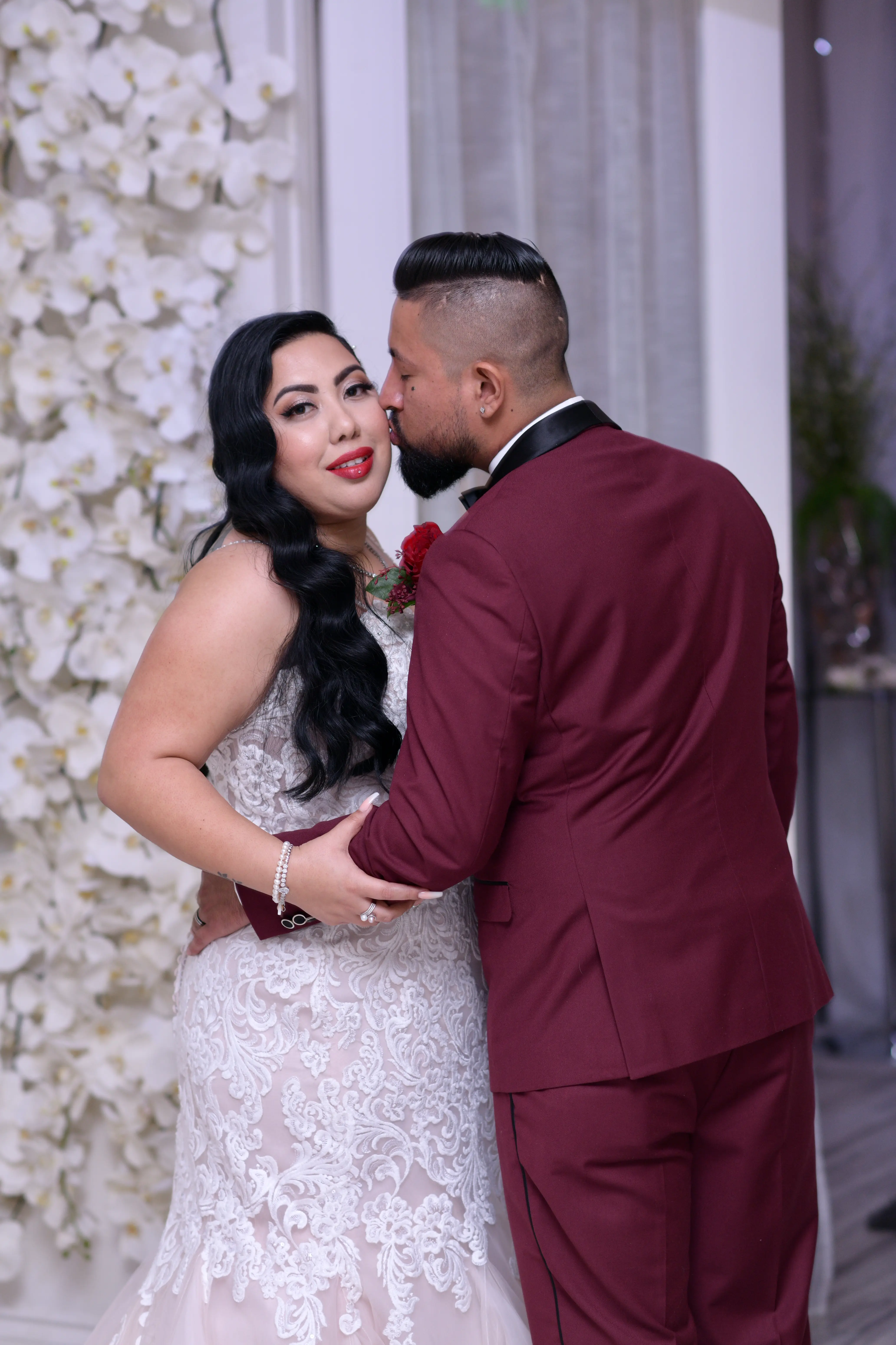 Groom kissing bride on the cheek who is wearing wedding dress called Alistaire Lynette.