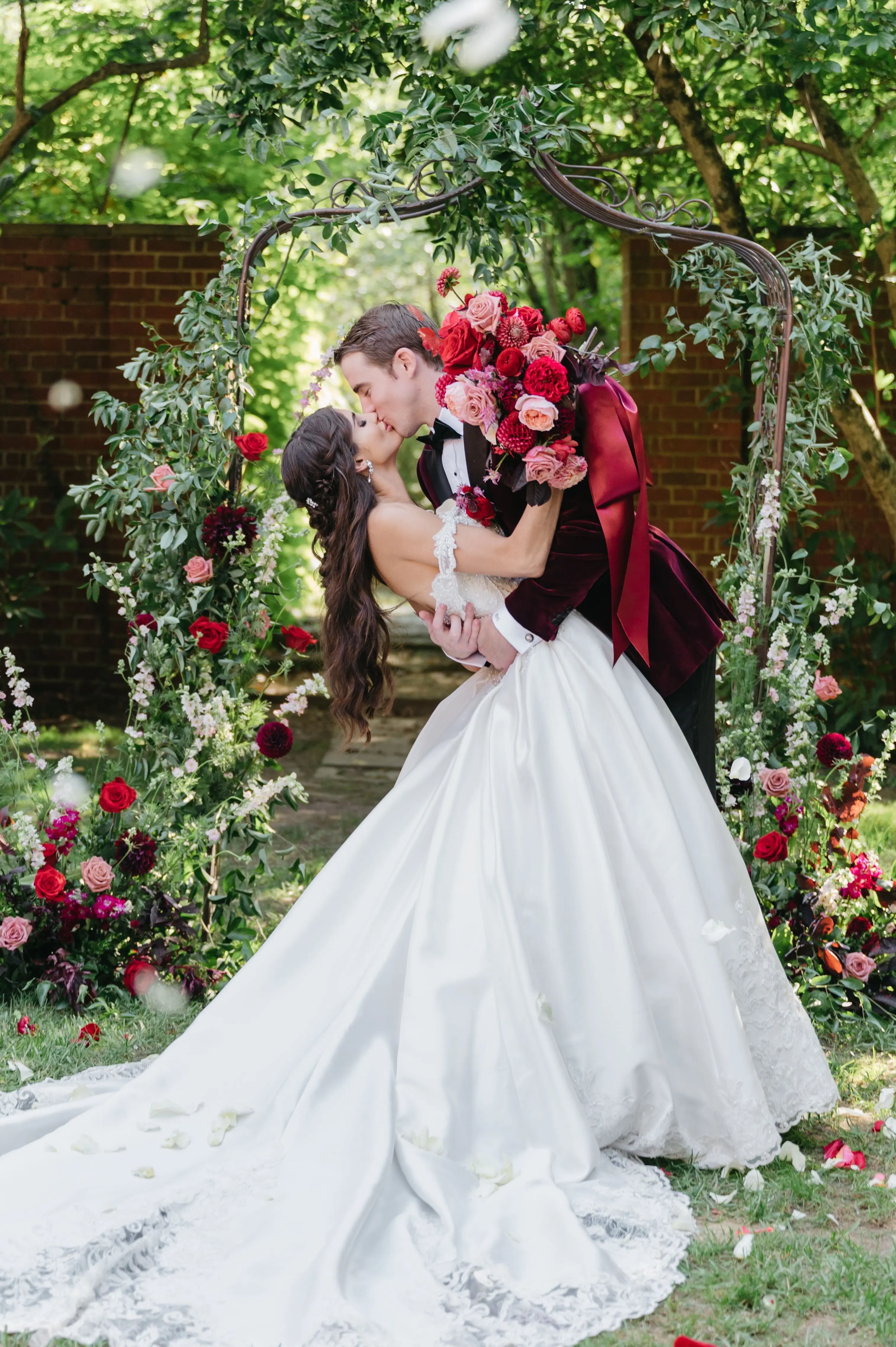 Bride In Satin Ballgown Wedding Dress Called Kimora By Sottero And Midgley With Groom In Suit At Wedding Arch