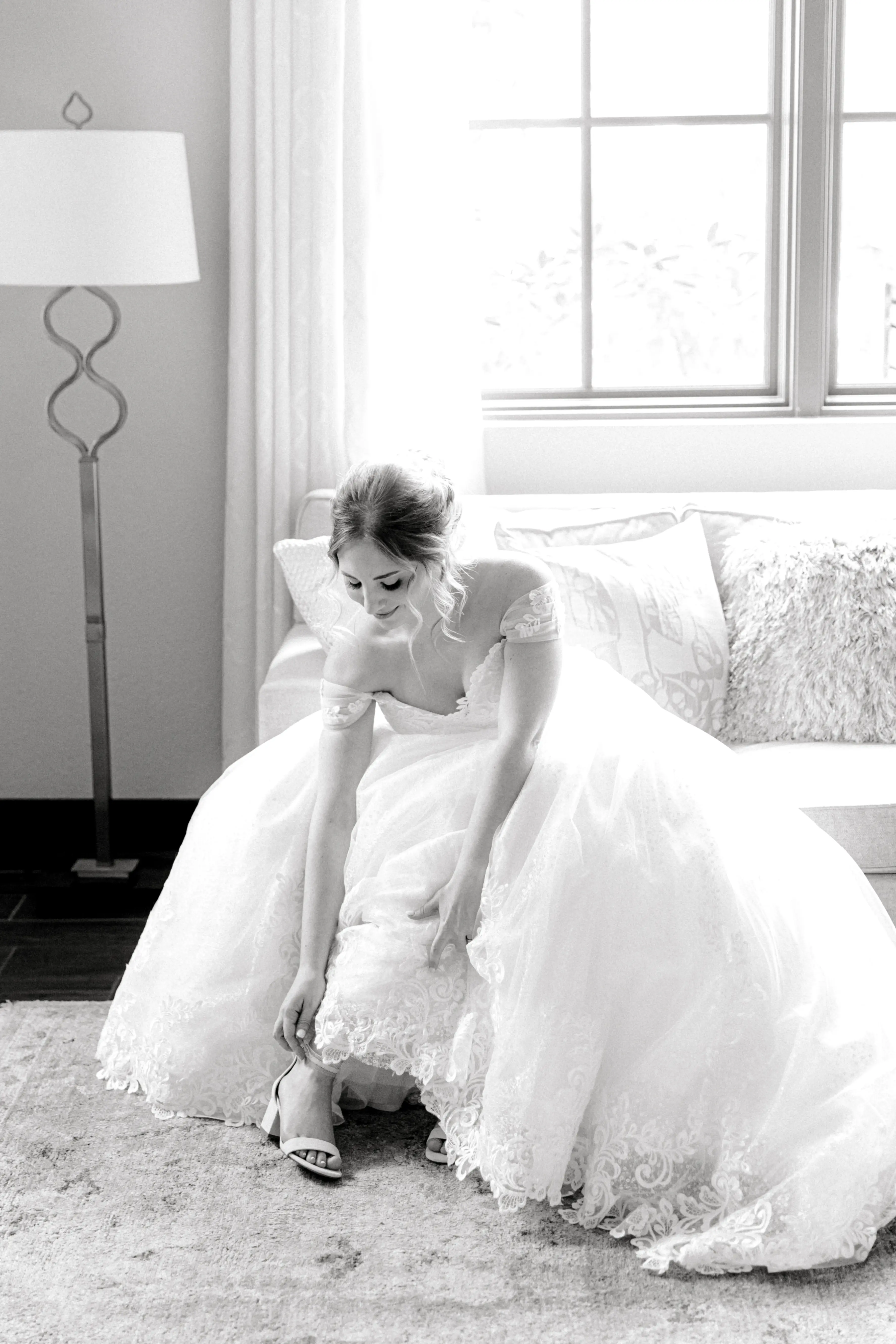 Bride Putting On Shoes While Wearing Chic Lace Ball Gown Wedding Dress Called Tristyn By Maggie Sottero