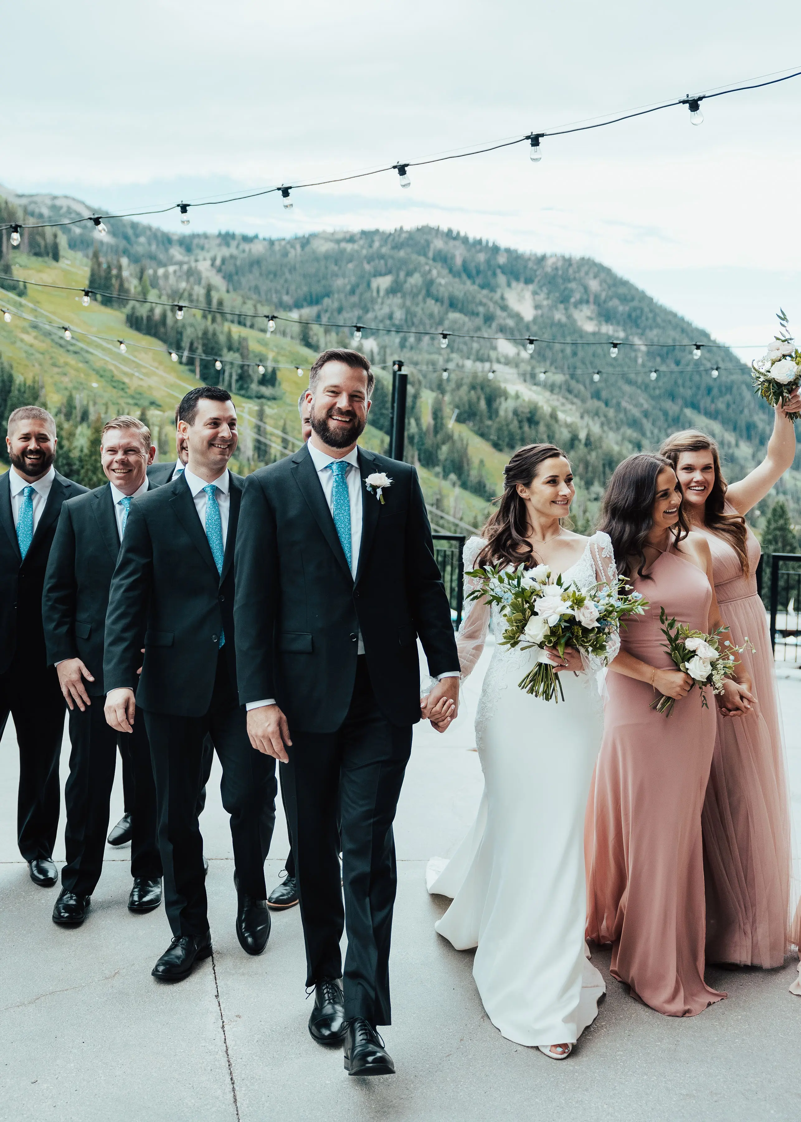 Bride Wearing Long Sleeve Lace Mermaid Wedding Dress with Groom and Bridal Party Outdoors.