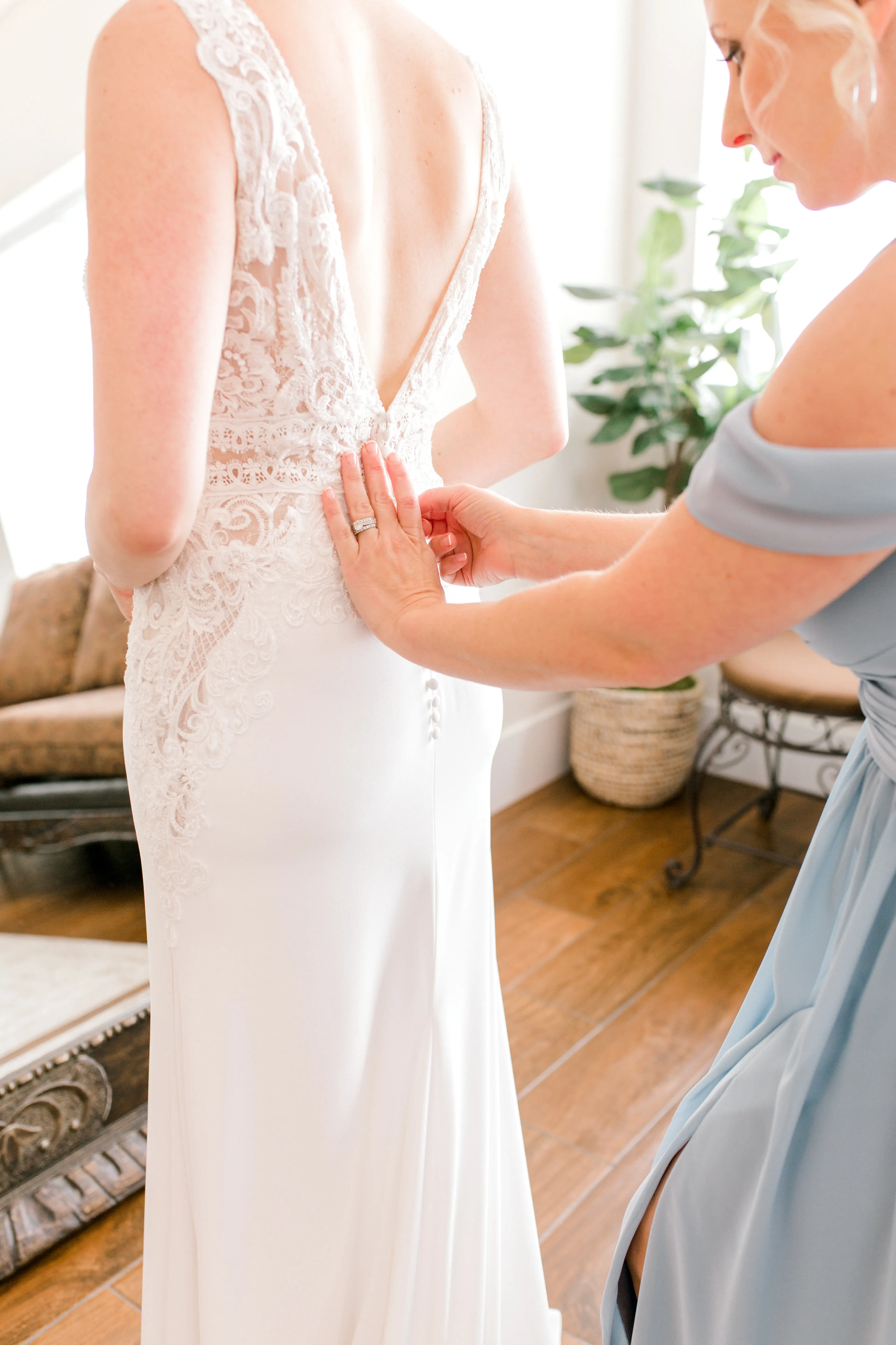 Bridesmaid fastening the brides dress called Aidan by Maggie Sottero.