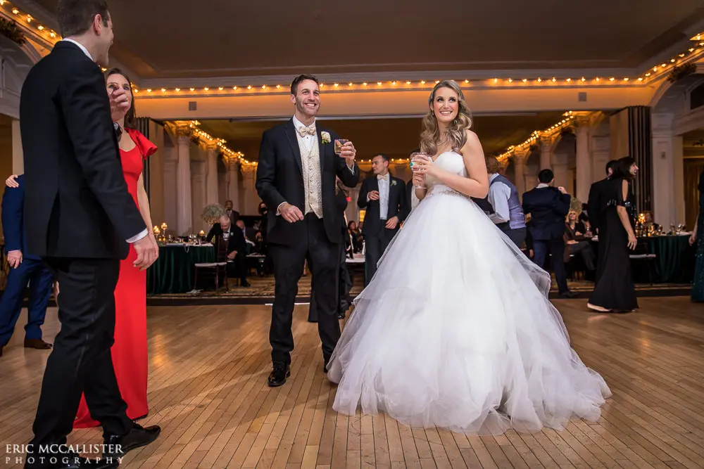 Bride dancing with groom wearing strapless ballgown tulle wedding dress with sweetheart neckline indoors on dance floor.