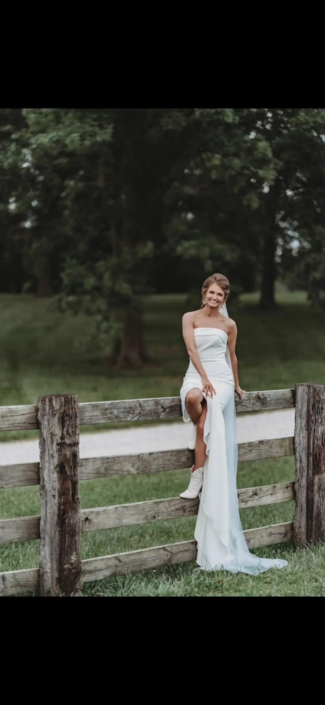 Bride Wearing Simple Fit And Flare Wedding Dress Called Francine By Rebecca Ingram Sitting On A Fence