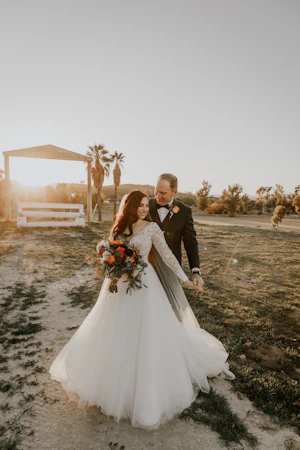 Bride And Groom Standing Together During Sunset. Bride Wearing Beautiful Boho Long Sleeve Ball Gown Called Mallory Dawn By Maggie Sottero