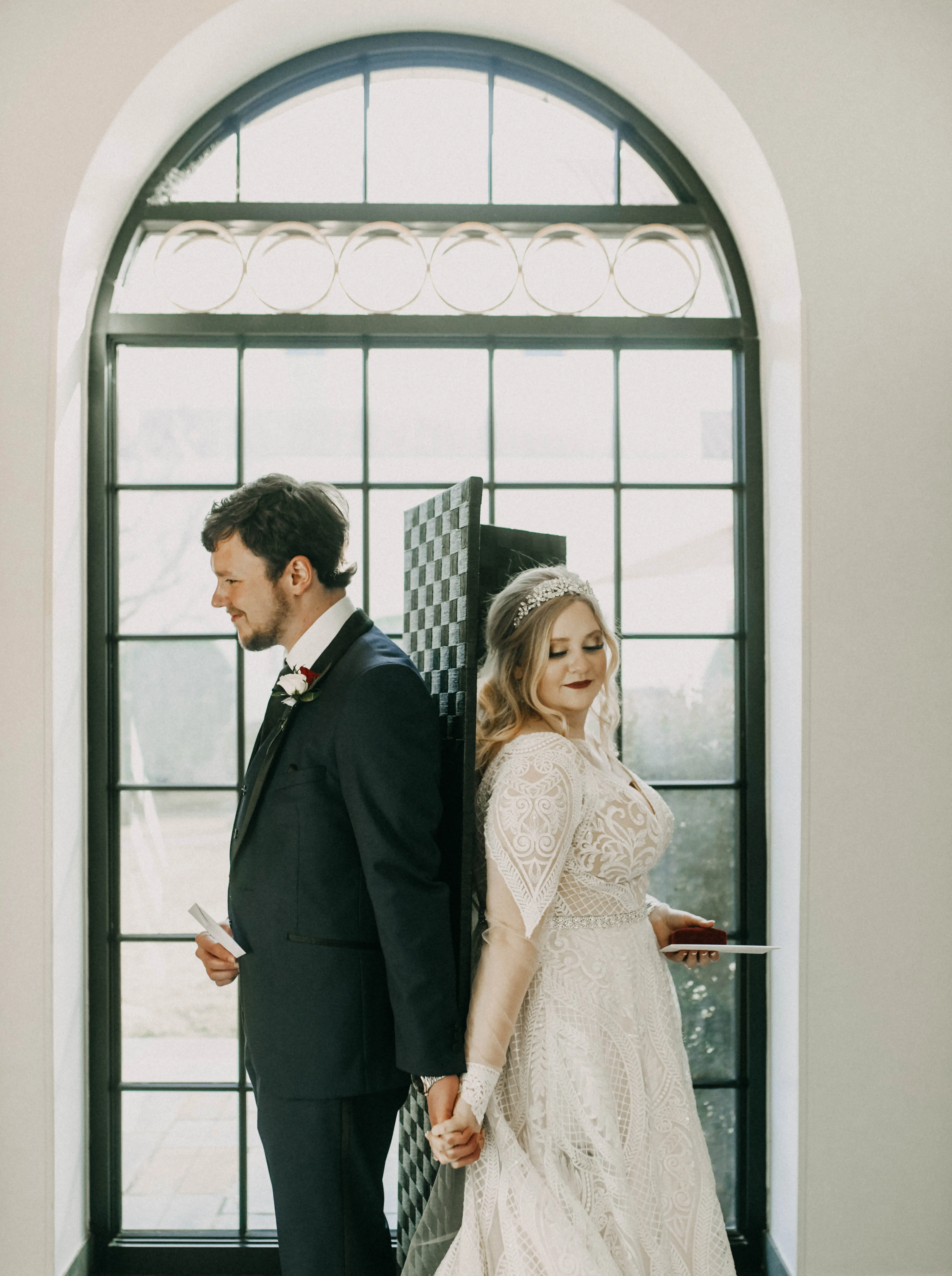 Bride and groom back to back holding hands.