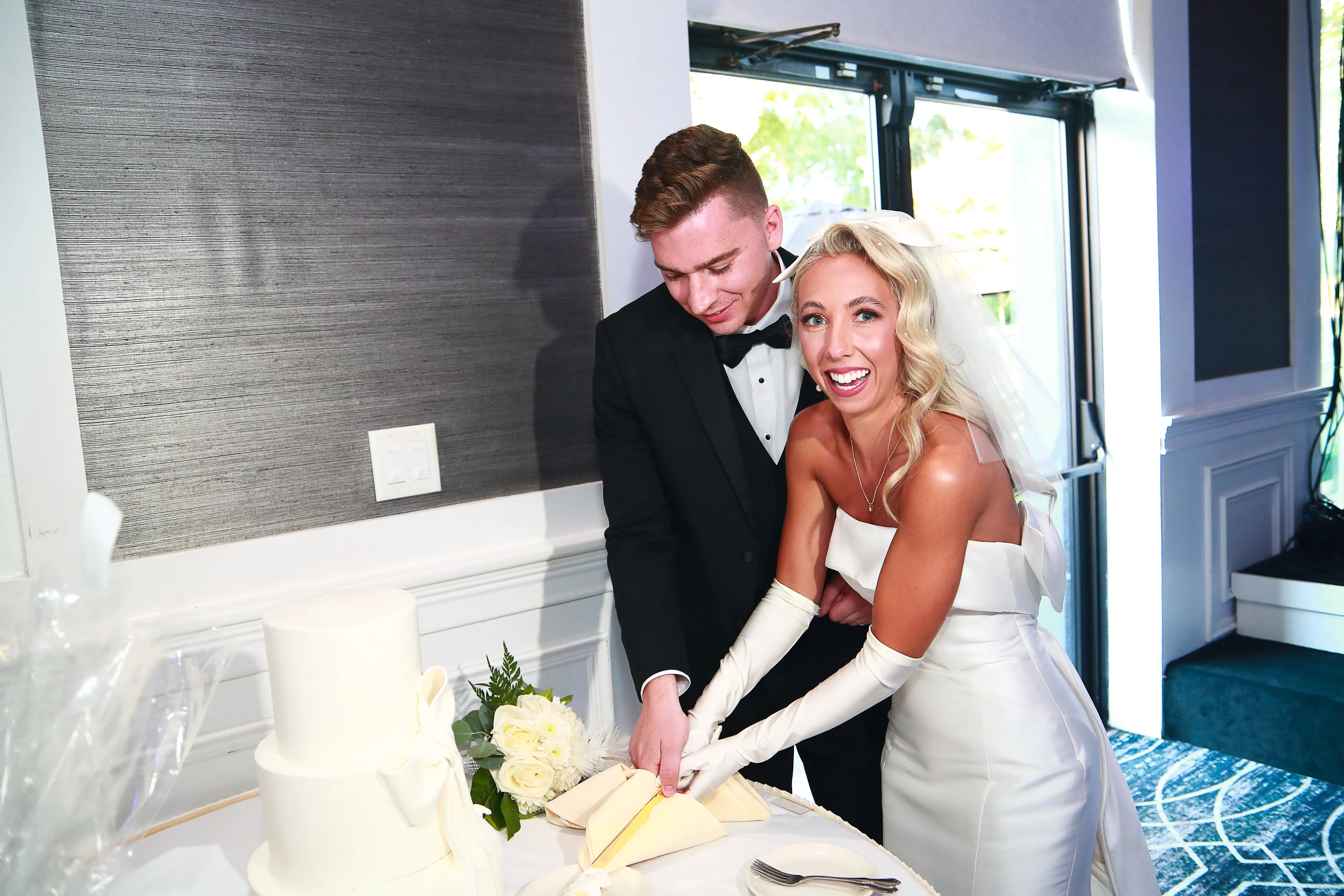 Bride In Satin Wedding Dress Called Michell By Maggie Sottero With Gloves Cutting Cake With Groom