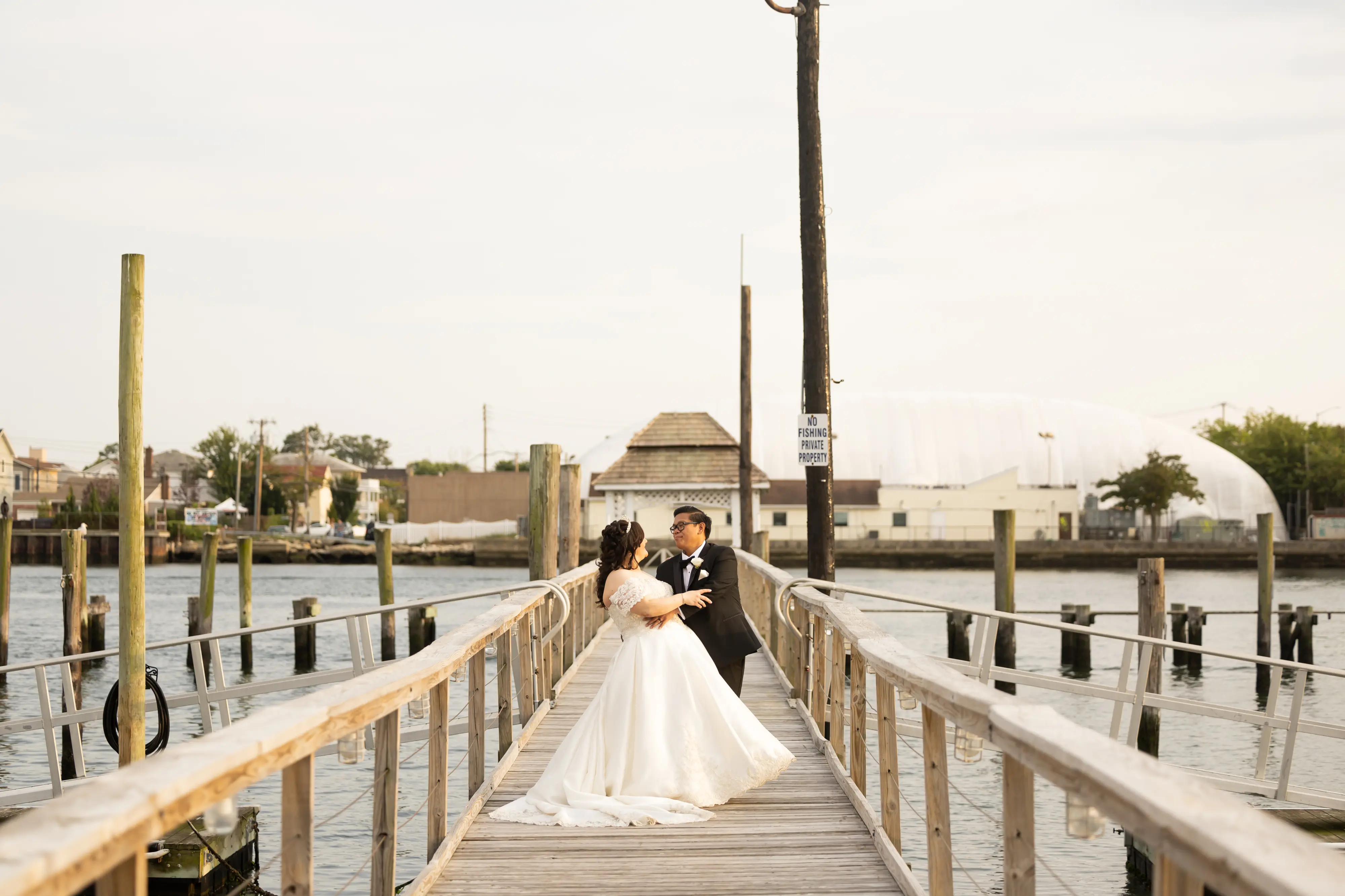 Bride in Satin Ball Gown Wedding Dress Featuring Decadent Beaded Lace Bodice, Kimora by Sottero & Midgley on Pier with Groom