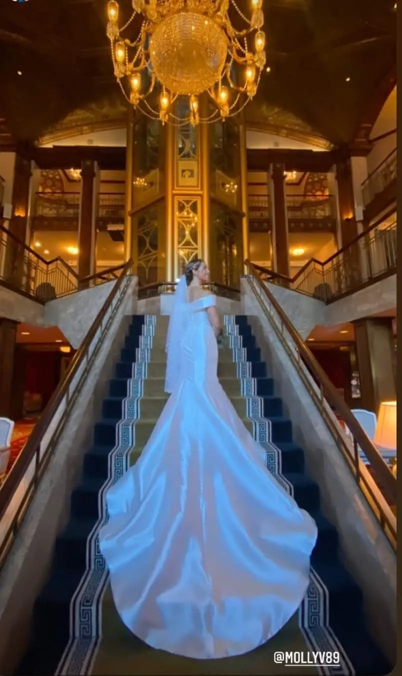 Bride Wearing Simple Fit And Flare Wedding Dress Called Josie By Rebecca Ingram On The Stairs