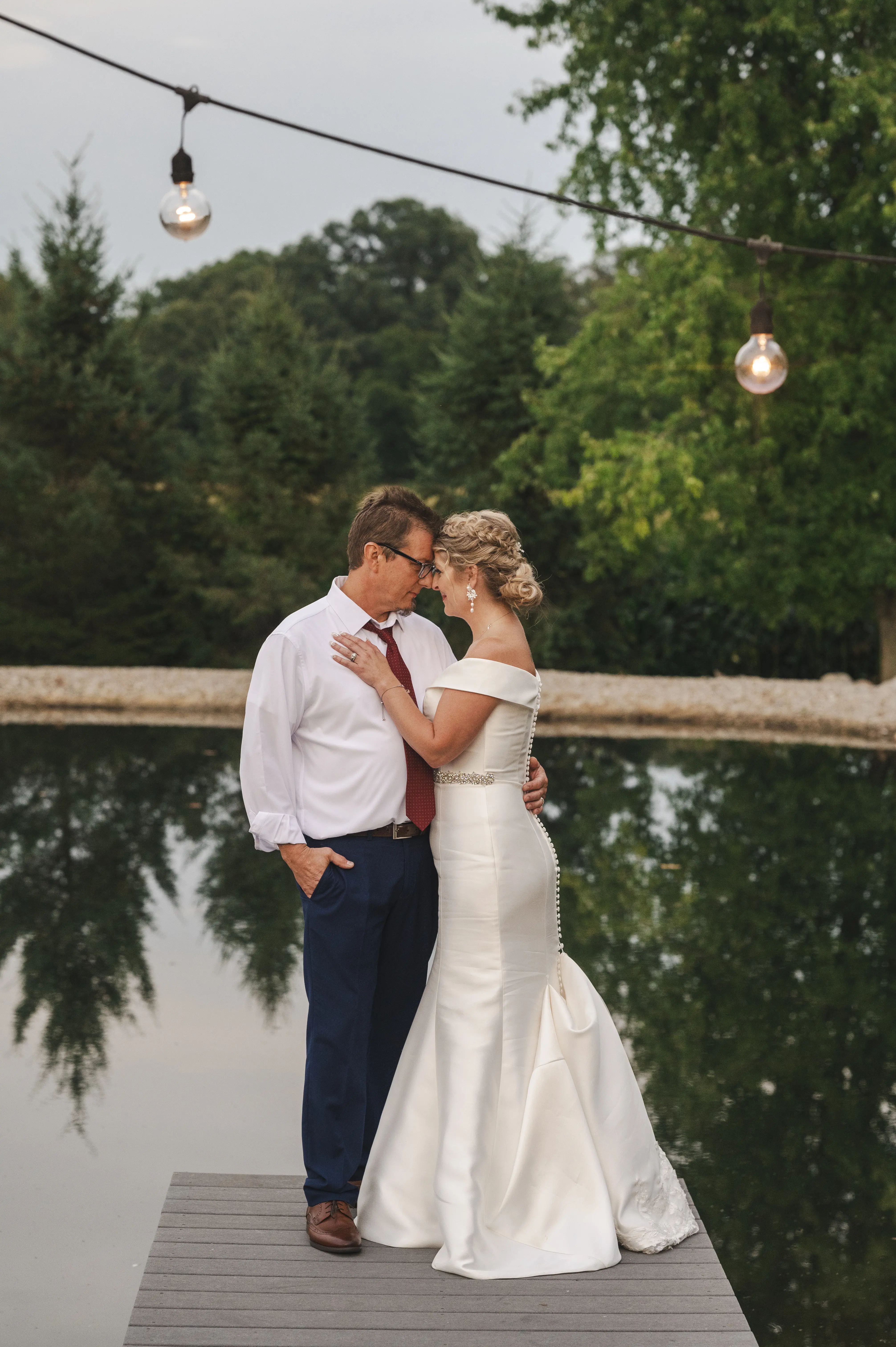 Bride wearing Josie by Rebecca Ingram cuddling with her husband on a dock