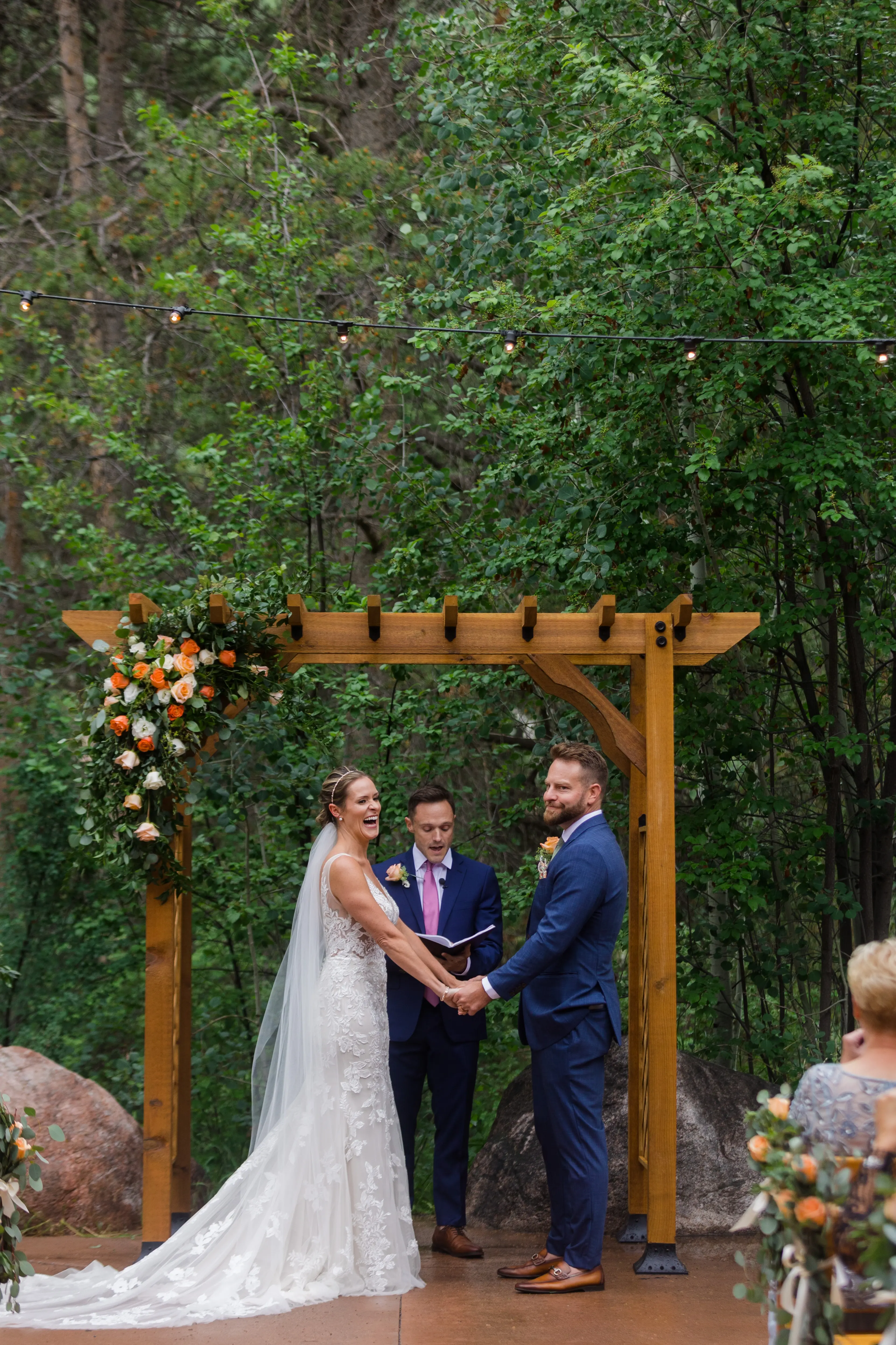 Bride laughing while getting married holding hands with husband with funny look on his face.