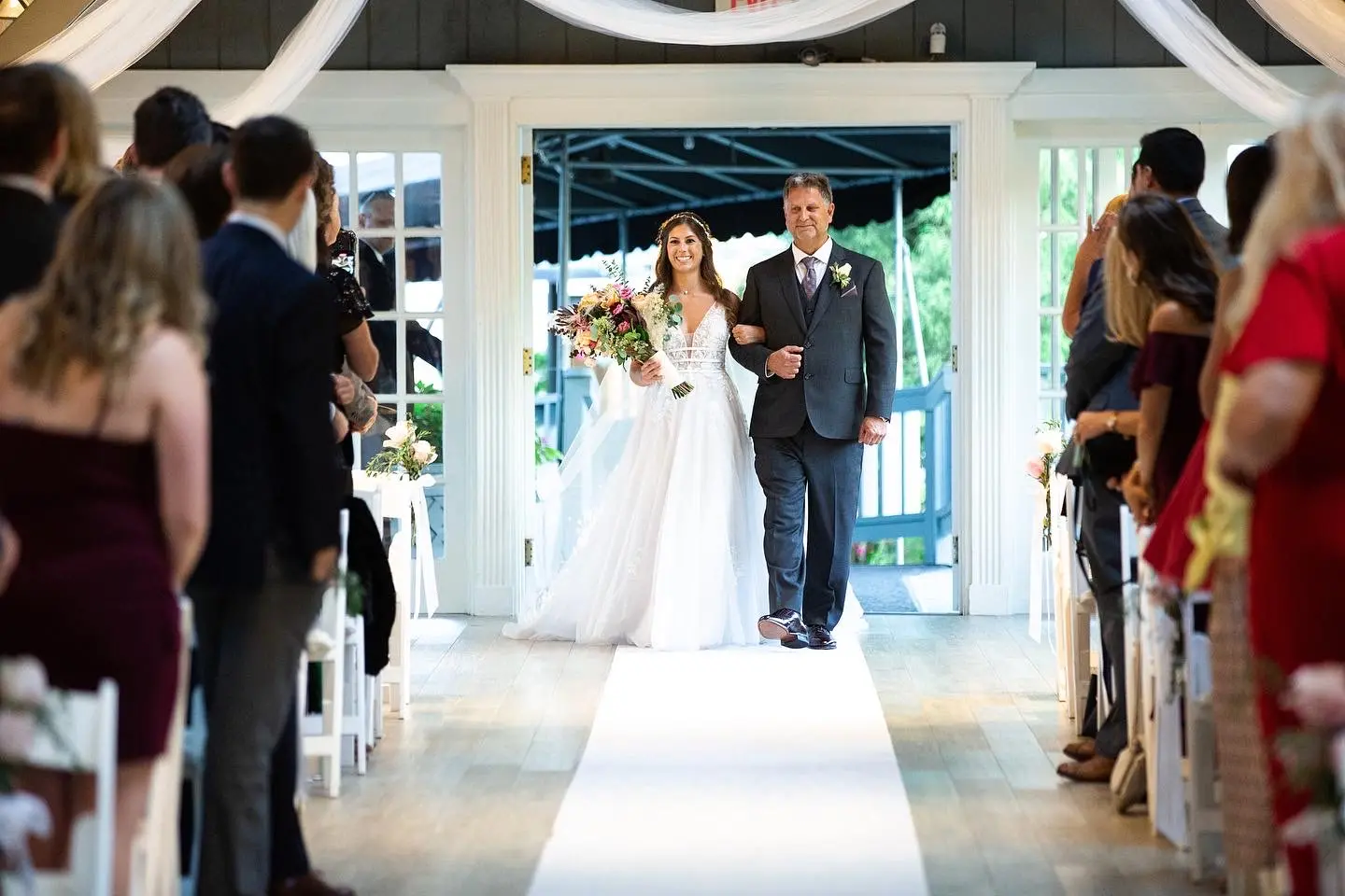 Bride walking down the aisle with her father wearing Lace A-line Wedding Dress called Raelynn by Rebecca Ingram