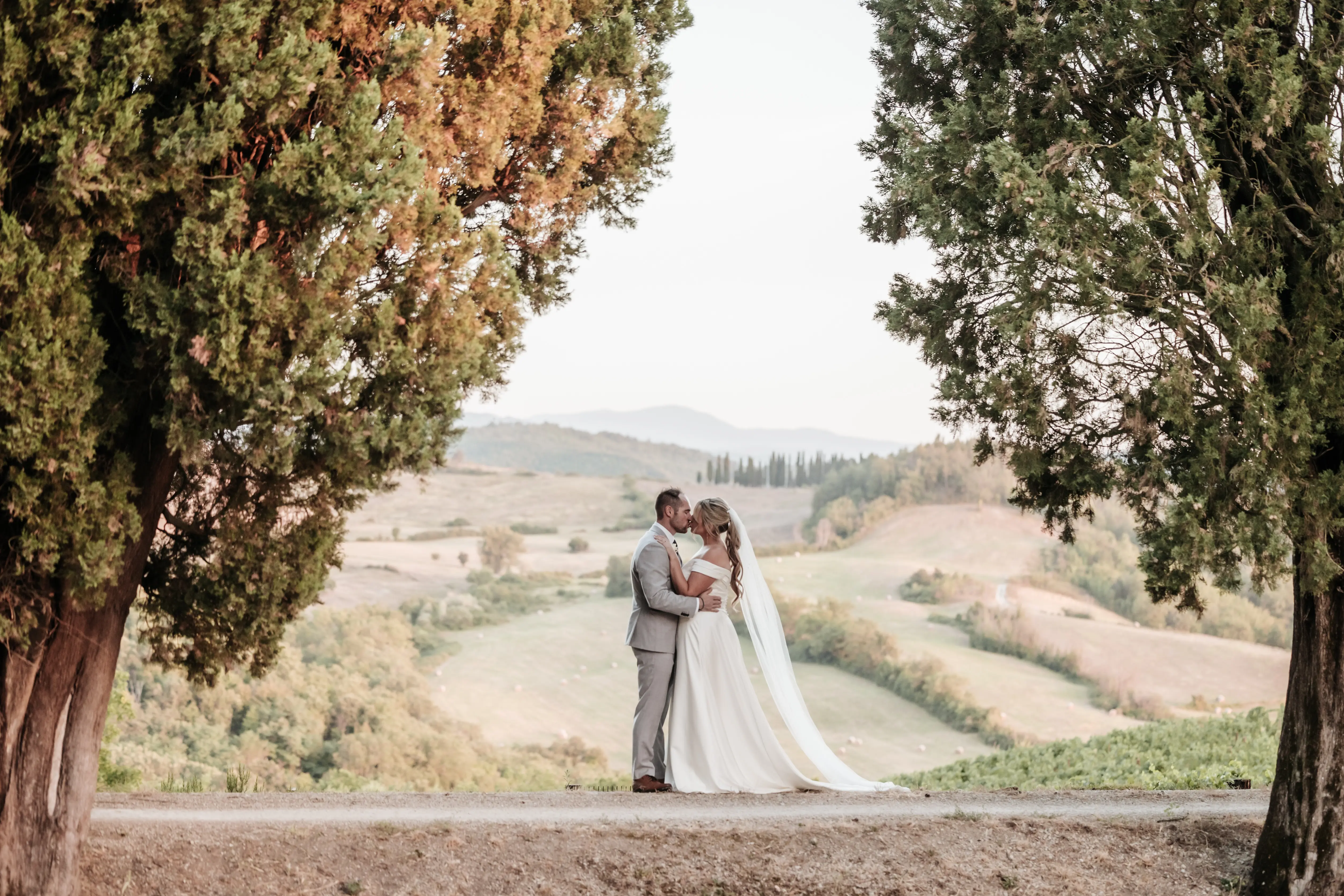Groom With Bride Wearing A-Line Satin Off-The-Shoulder Satin Wedding Dress Ekaterina By Maggie Sottero