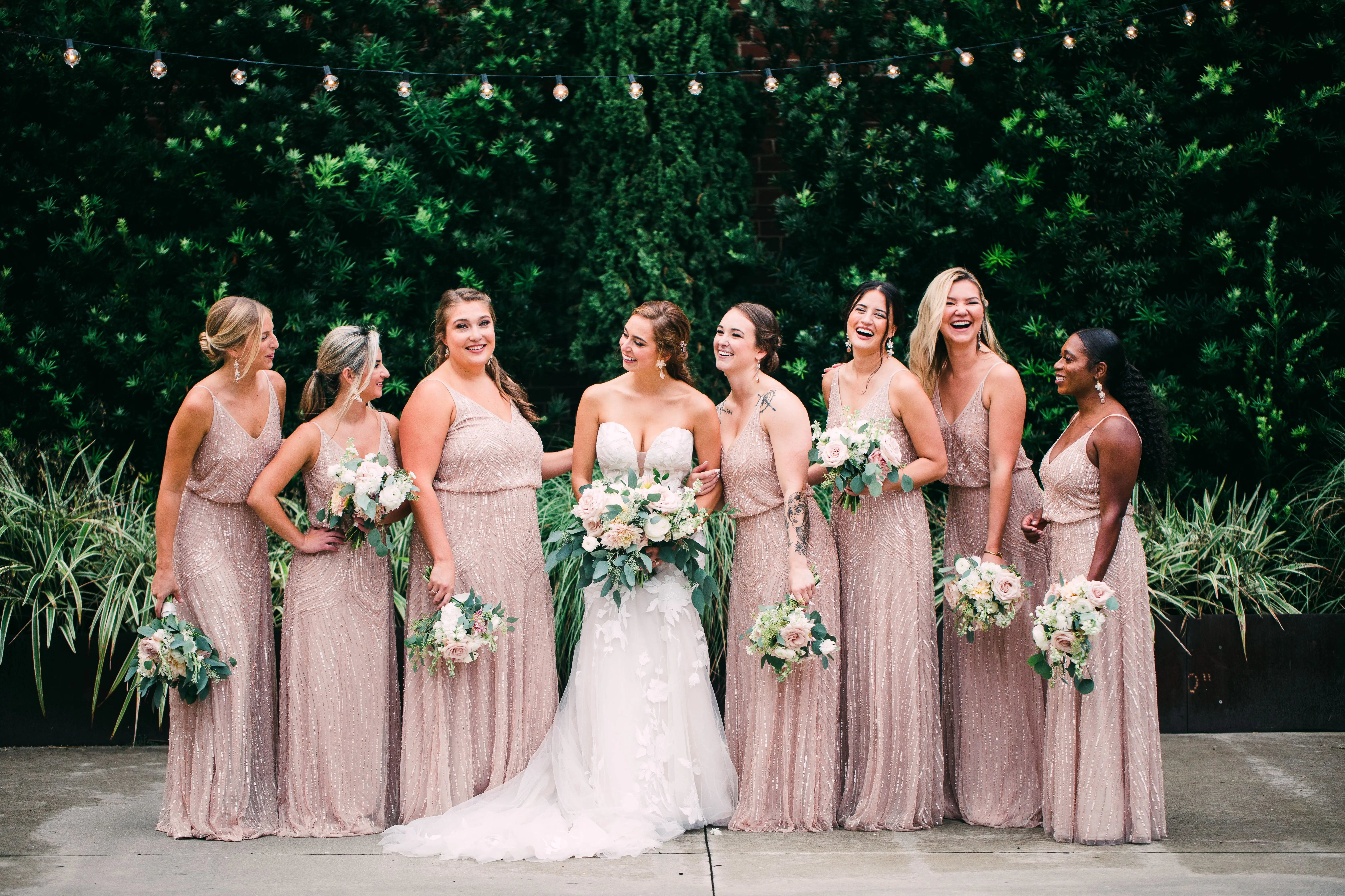 Bride with bridesmaids wearing strapless mermaid wedding dress with oversized lace