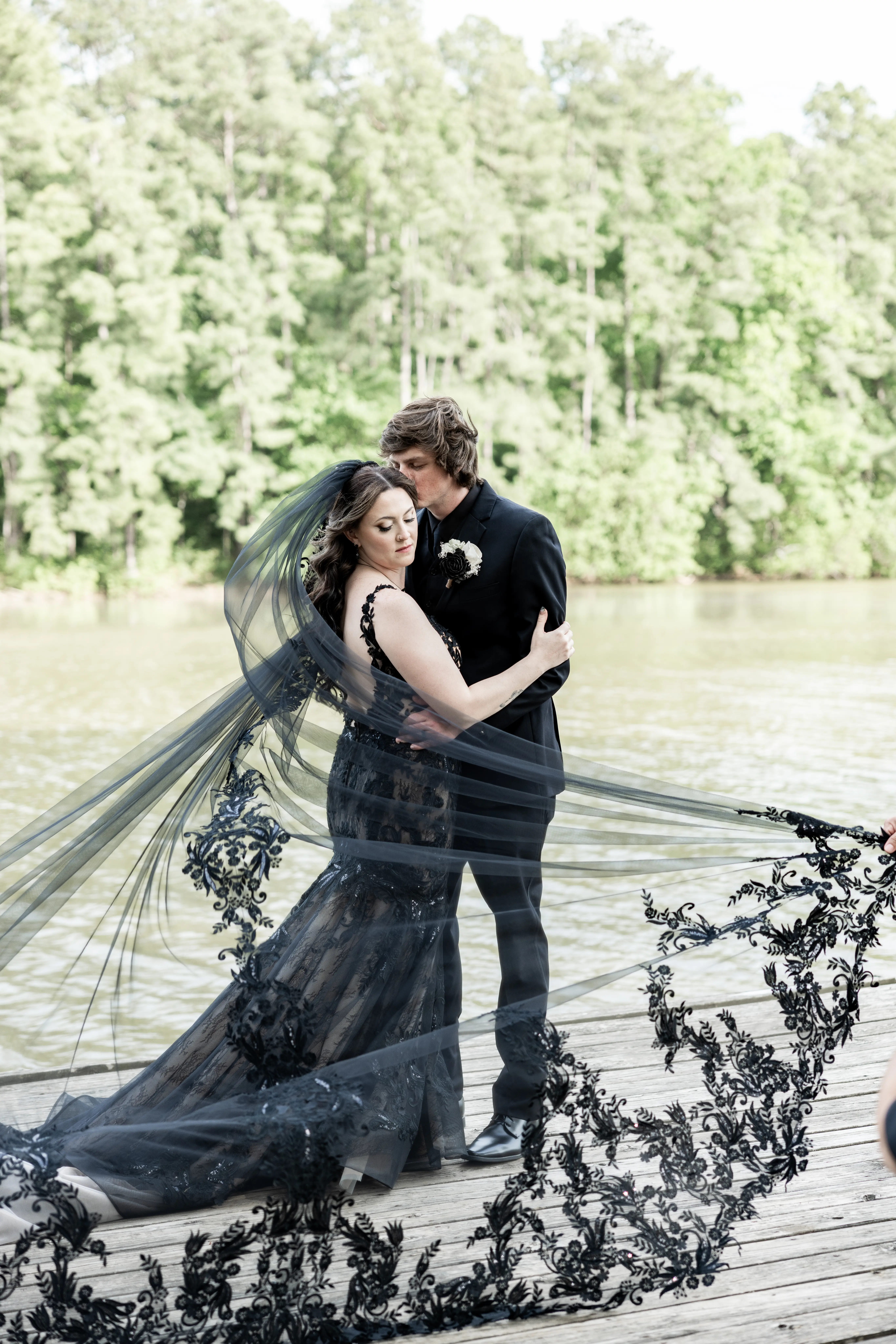 Bride wearing Zander Lane by Sottero and Midgley with a dramatic veil and her husband on a dock