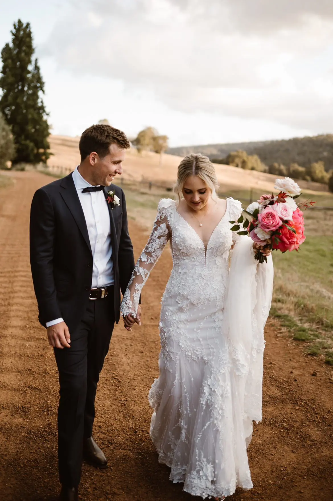 Groom Holding Hands with Bride in VIntage Inspired Puff Sleeve Mermaid Wedding Dress in 3-D Floral Motifs Called Cruz by Sottero & Midgley