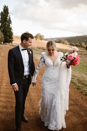 Groom Holding Hands with Bride in VIntage Inspired Puff Sleeve Mermaid Wedding Dress in 3-D Floral Motifs Called Cruz by Sottero & Midgley
