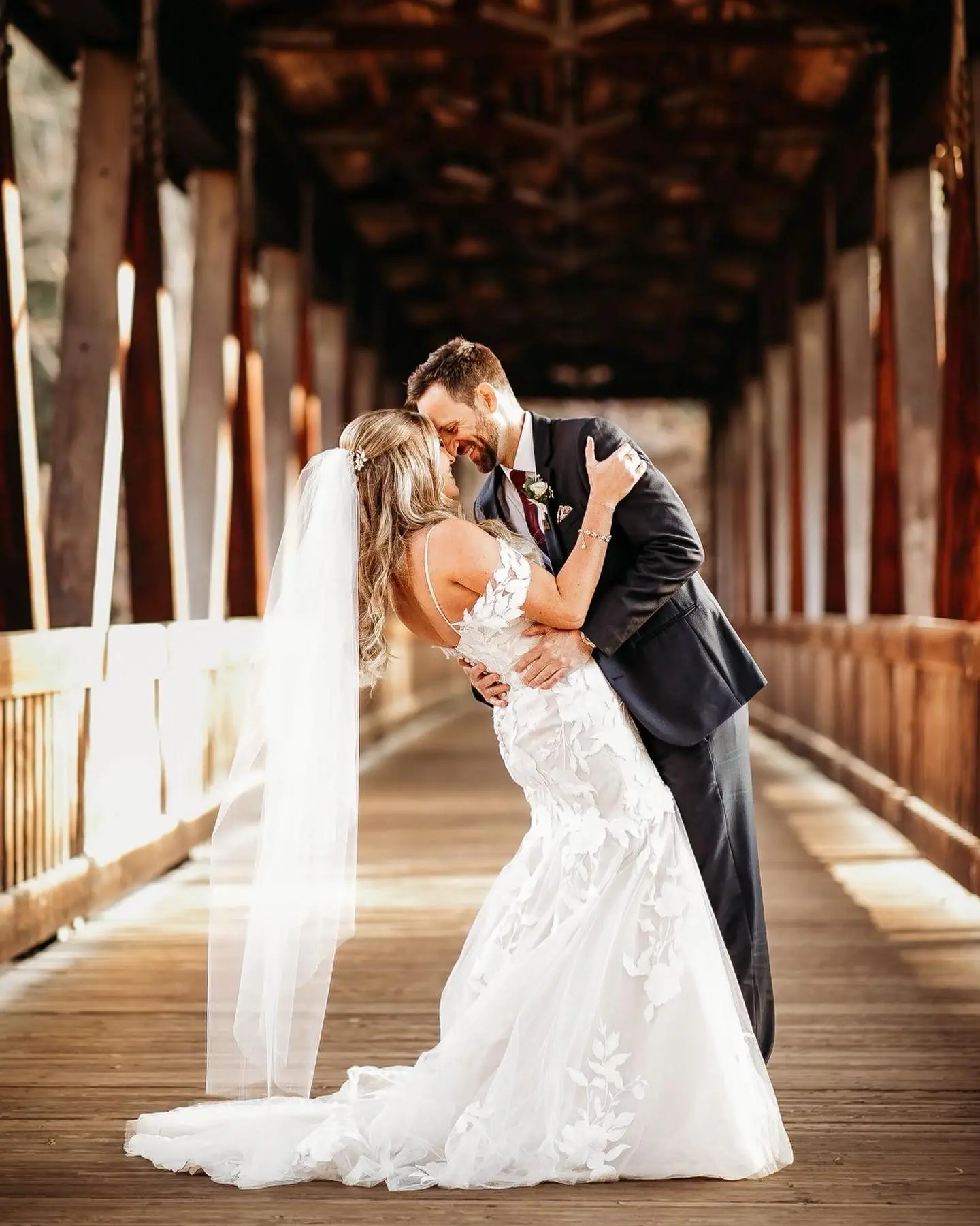 Bride And Groom Standing Together. Bride Wearing Mermaid Wedding Dress With Oversized Lace Called Hattie By Rebecca Ingram