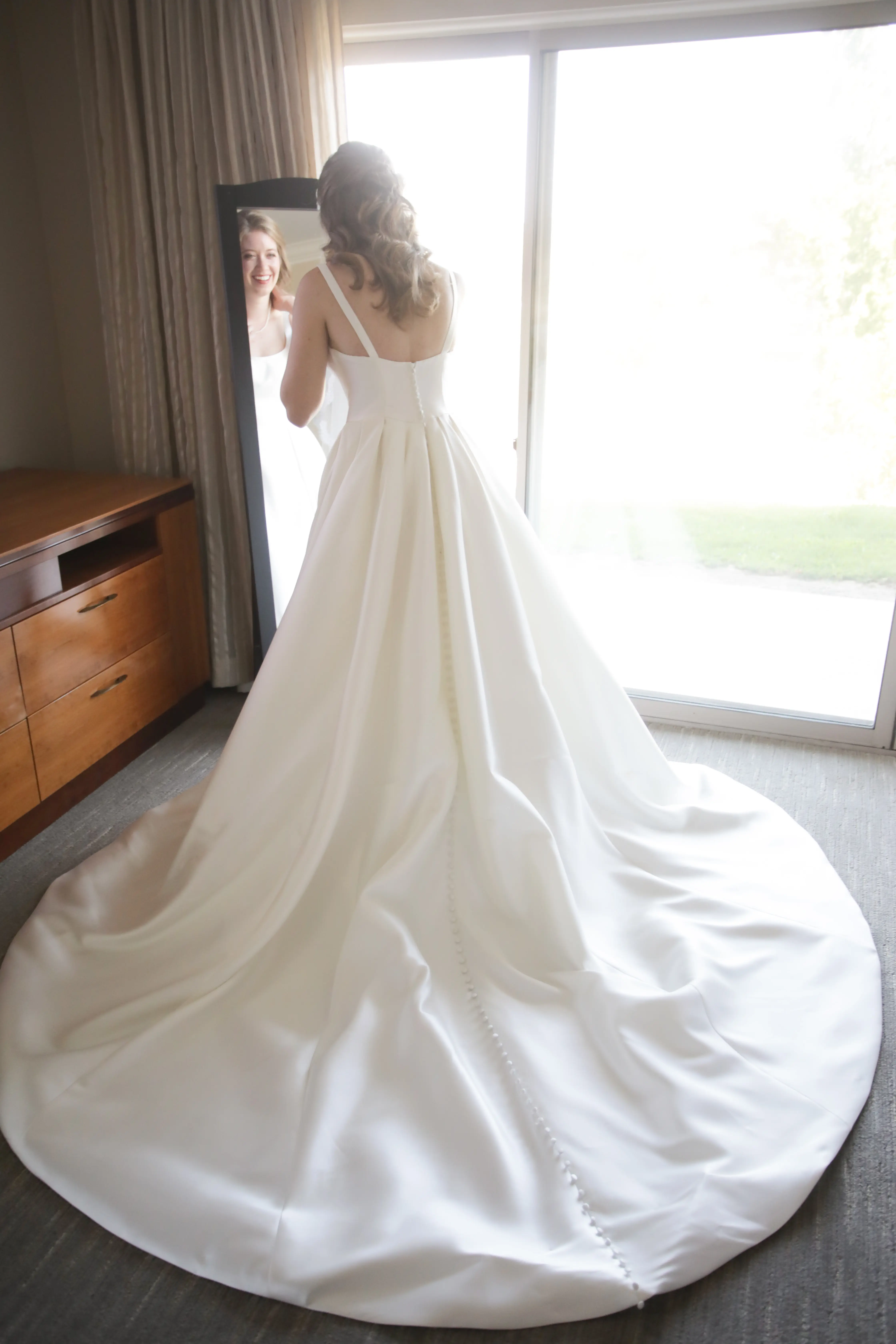 Bride wearing Simple Ballgown Wedding Dress called Selena by Maggie Sottero while looking in a mirror