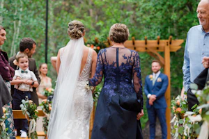 Back view of bride being walked down the aisle by her mother.