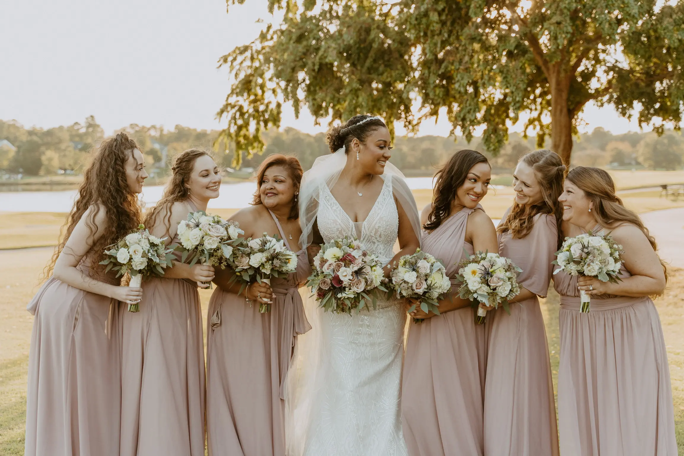 Bride with bridesmaids wearing art deco-inspired beaded wedding dress outdoors.