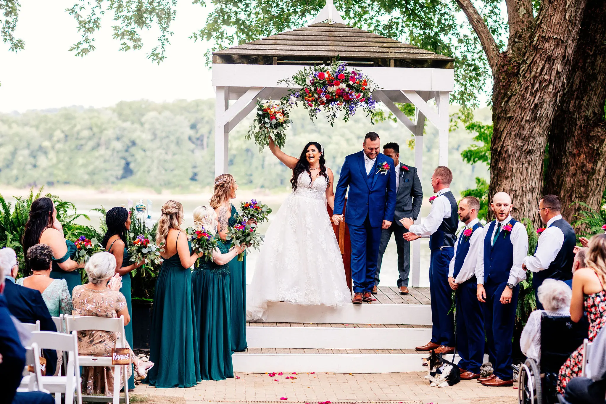 Bride wearing wedding dress called Valona holding up her colorful bouquet in celebration.