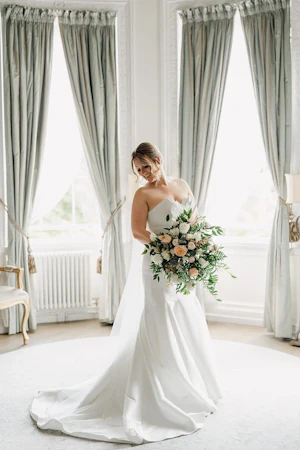 Bride Wearing Modern Wedding Dress Called Marilyn By Sottero And Midgley Holding Pastel Rose Bouquet