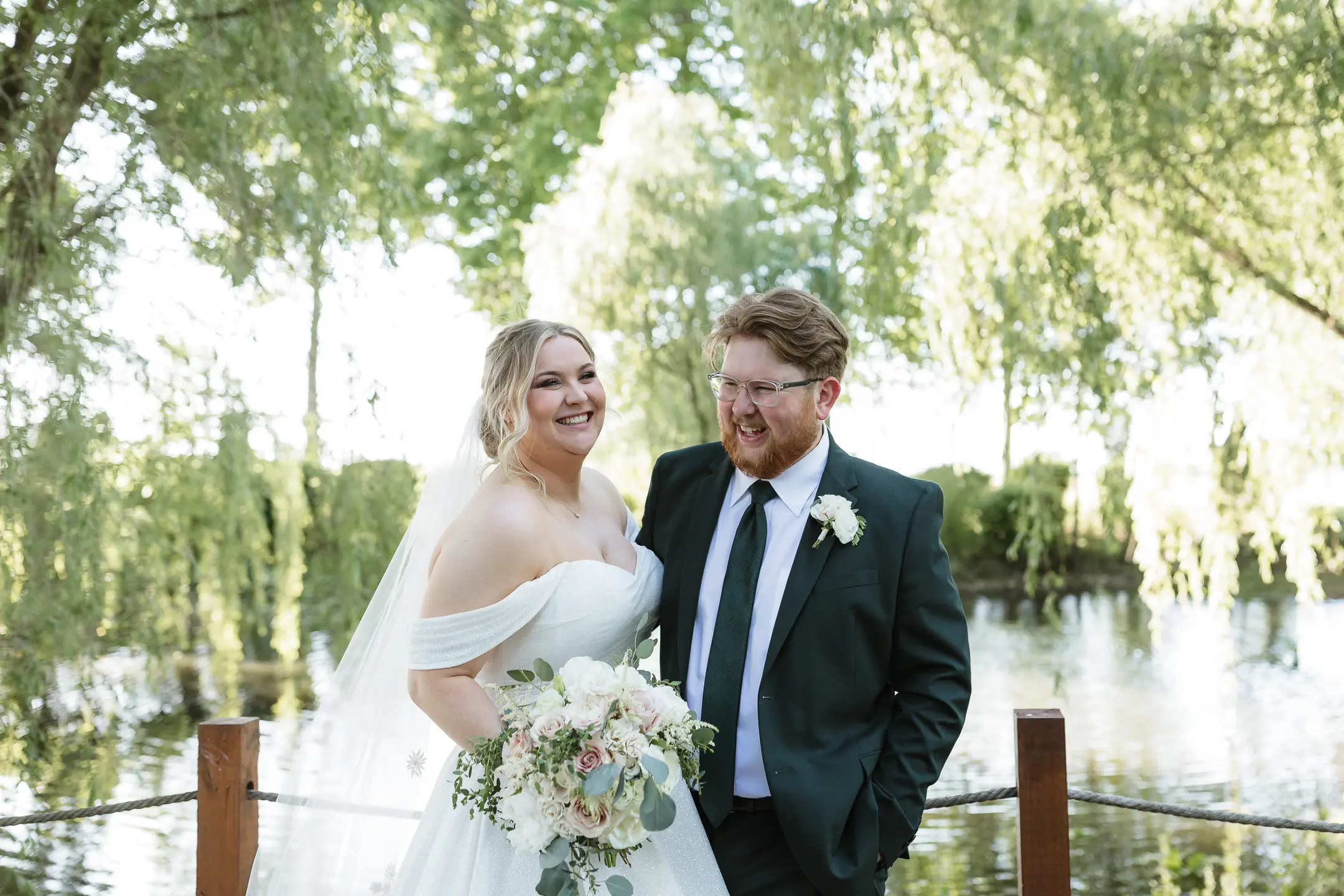 Bride wearing Anniston by Maggie Sottero in front of a lake with her husband
