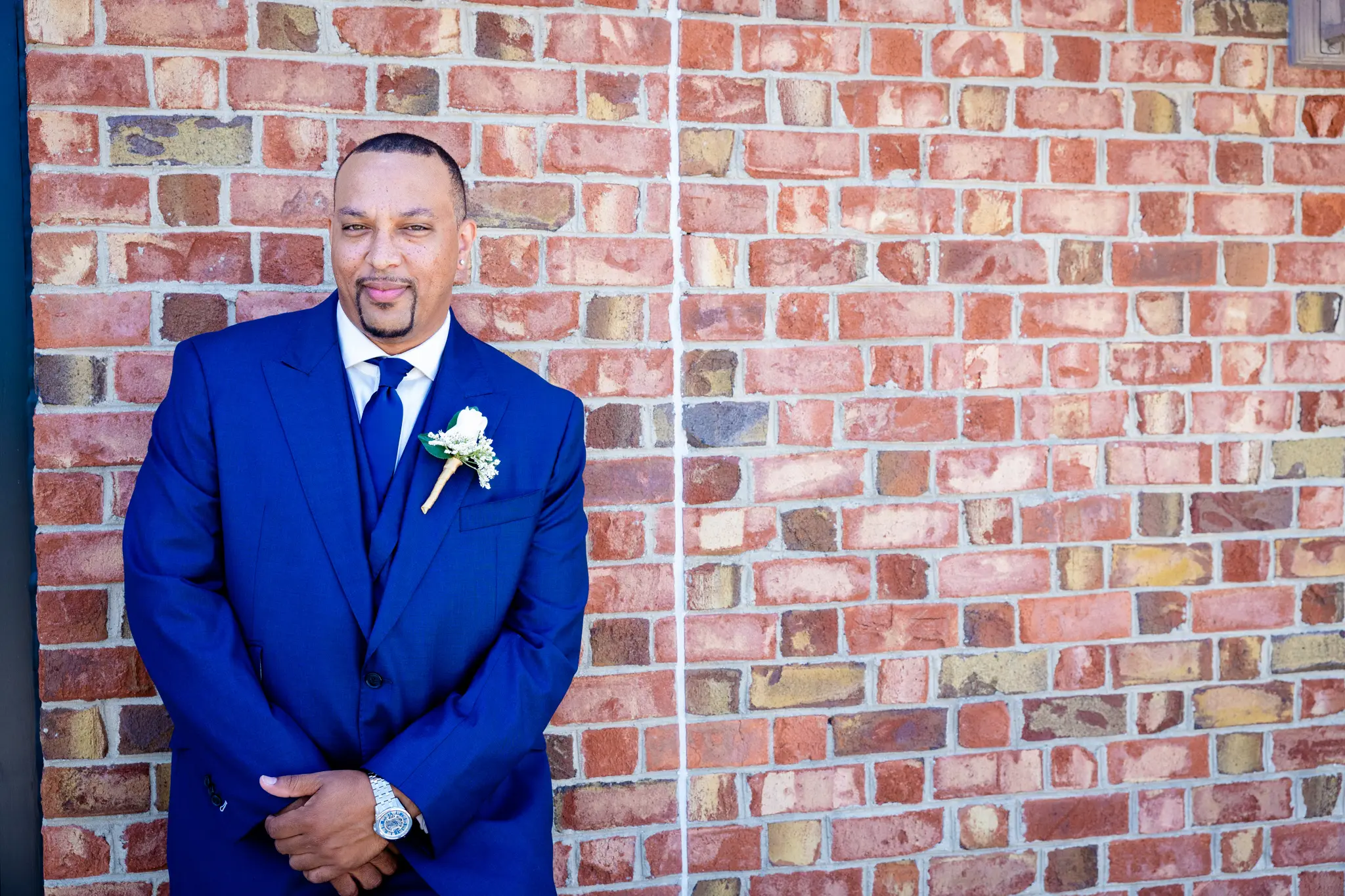 Groom Wearing Blue Suit Standing By Brick Wall