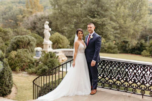 Bride wearing wedding dress called Roanne Rose stood at top of stairs with her groom.
