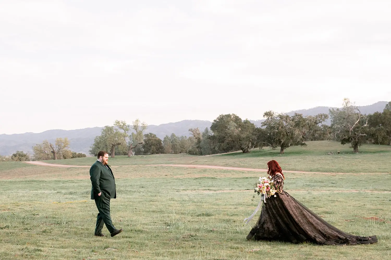Bride and groom walking towards each other across a field.
