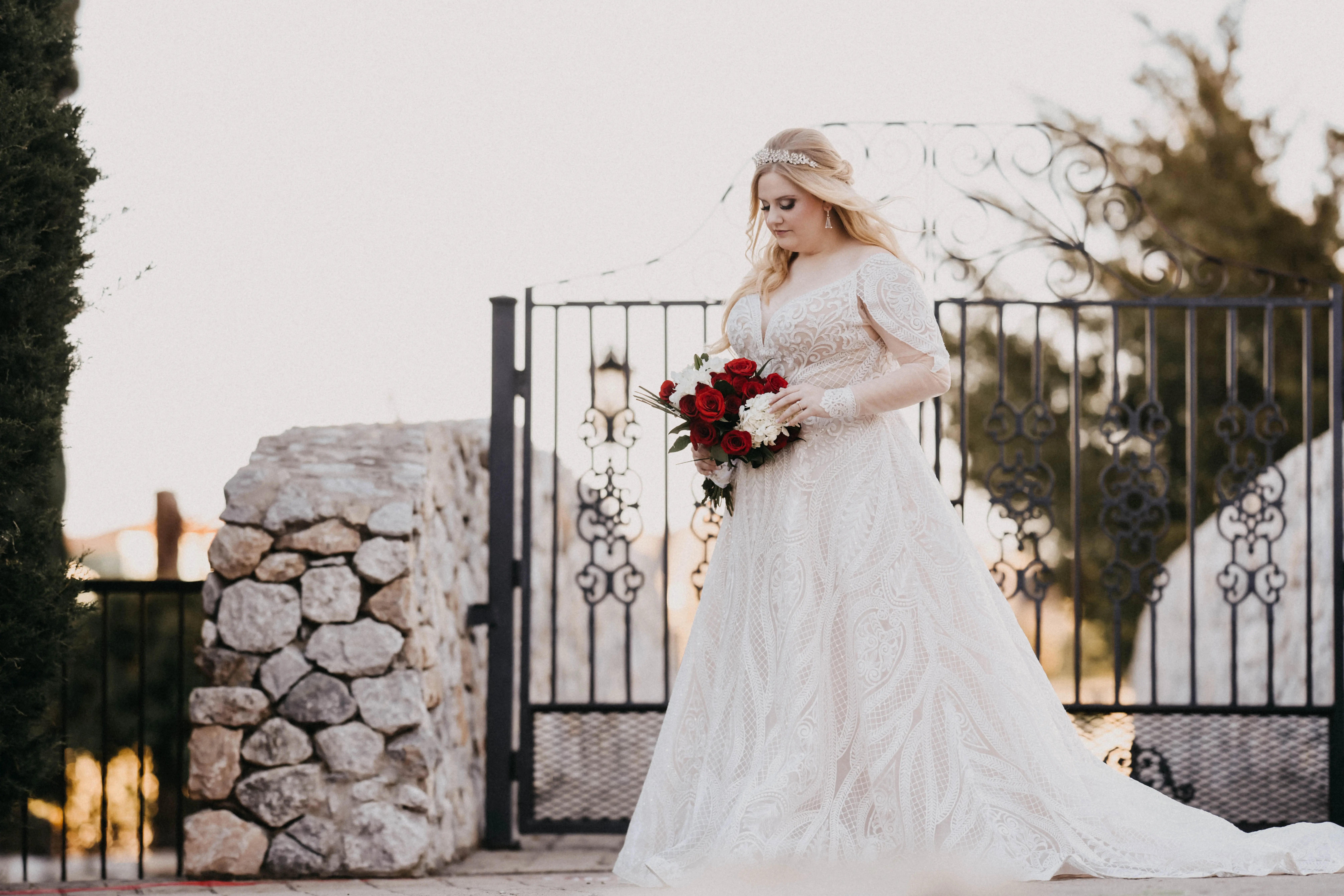 Bride looking down by old gate looking like a princess in her wedding dress called Roxanne with added customised sleeves.