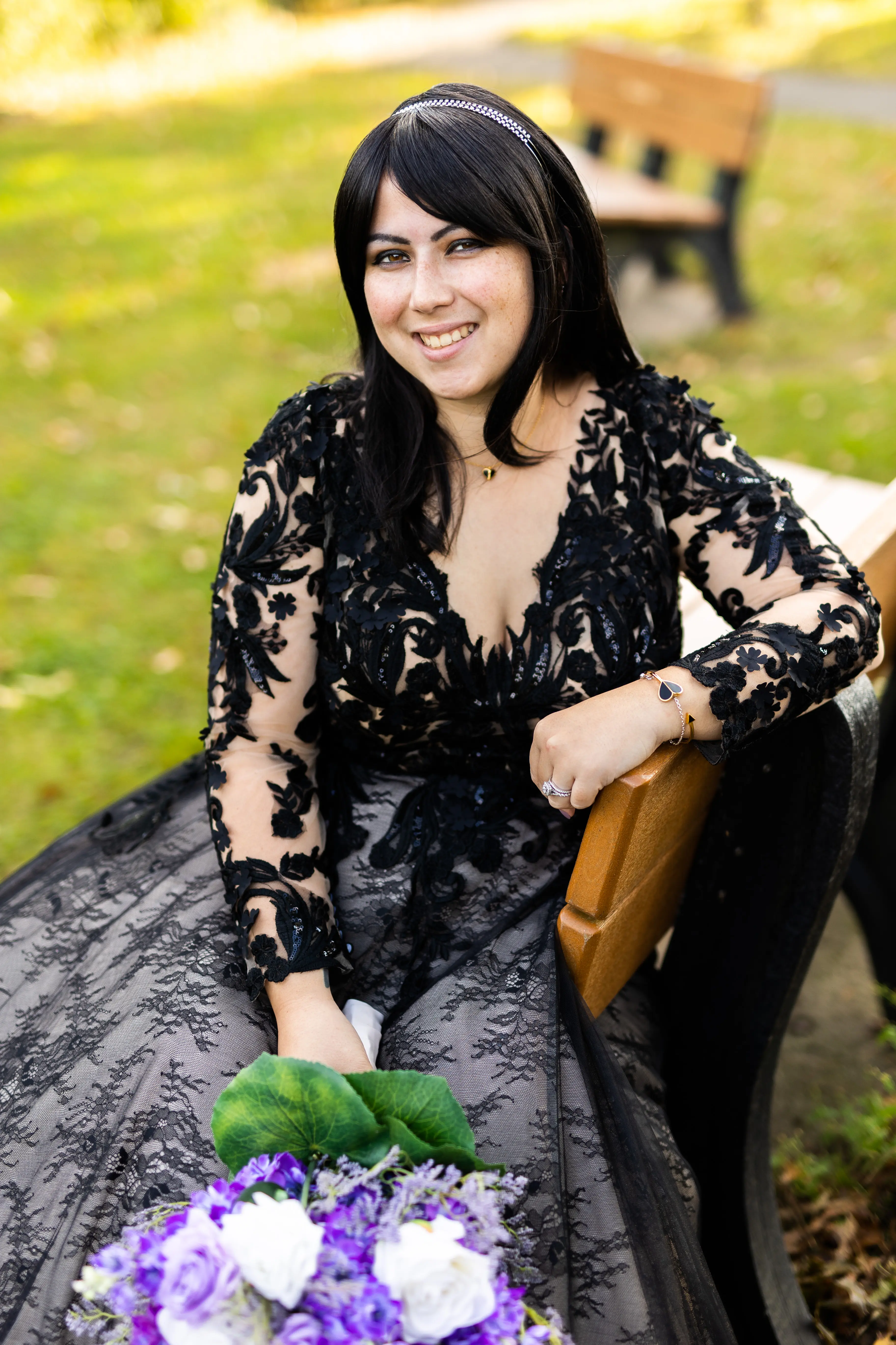 Bride Sitting Down Wearing Long Sleeve Black Lace Ballgown Wedding Dress Holding Bridal Bouquet.