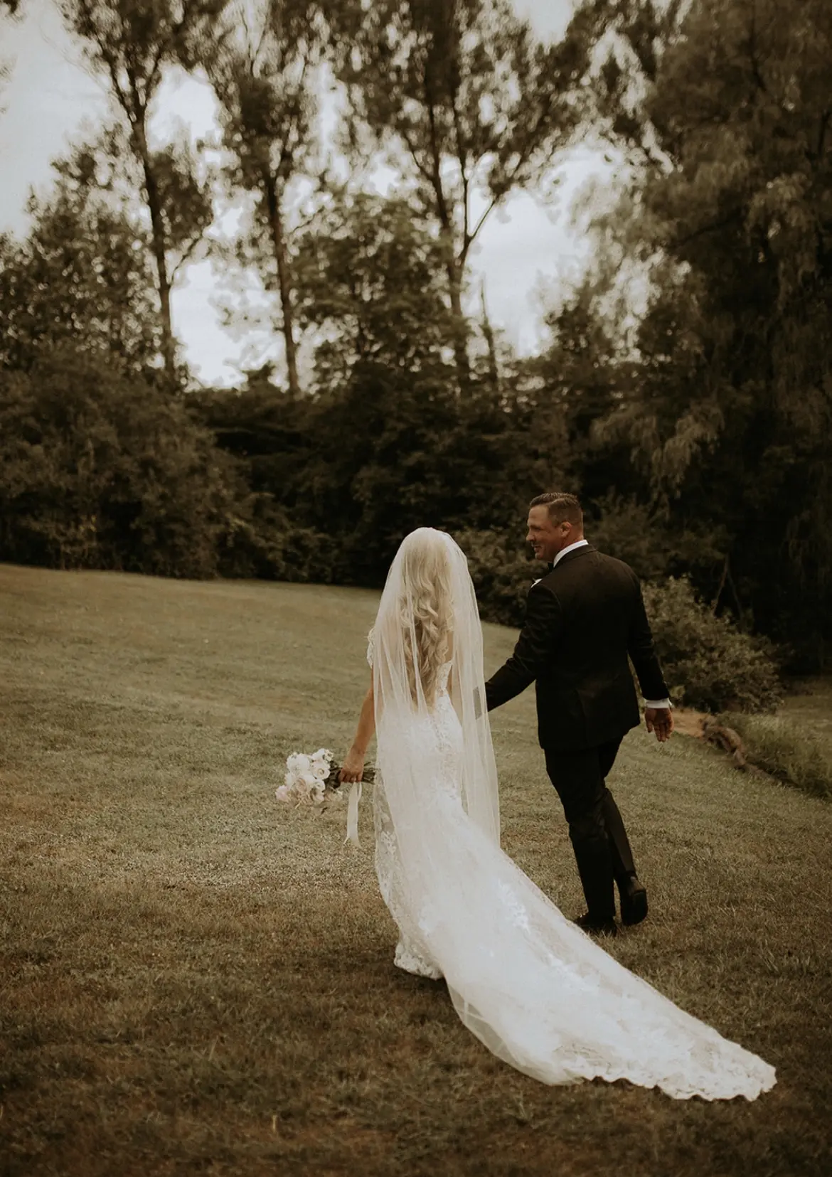 Bride wearing Lace Fit-and-Flare Wedding Dress called Tuscany Lynette by Maggie Sottero walking with her groom