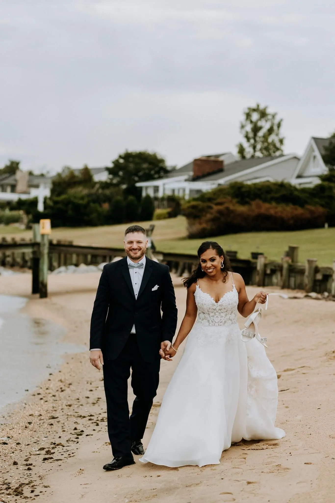 Bride Wearing Flirty A-line Wedding Gown Called Savannah By Maggie Sottero Walking On The Beach With Groom