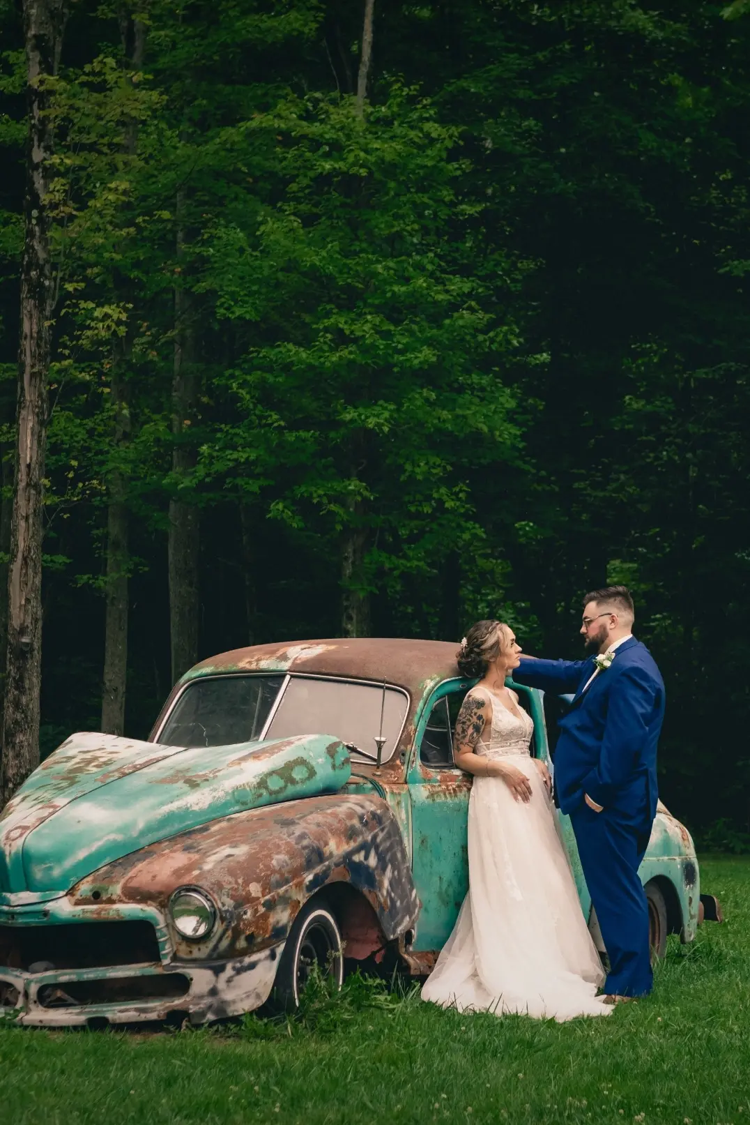 Bride wearing Boho Lace Wedding Dress called Raelynn by Rebecca Ingram and the groom next to an old vintage abandoned car