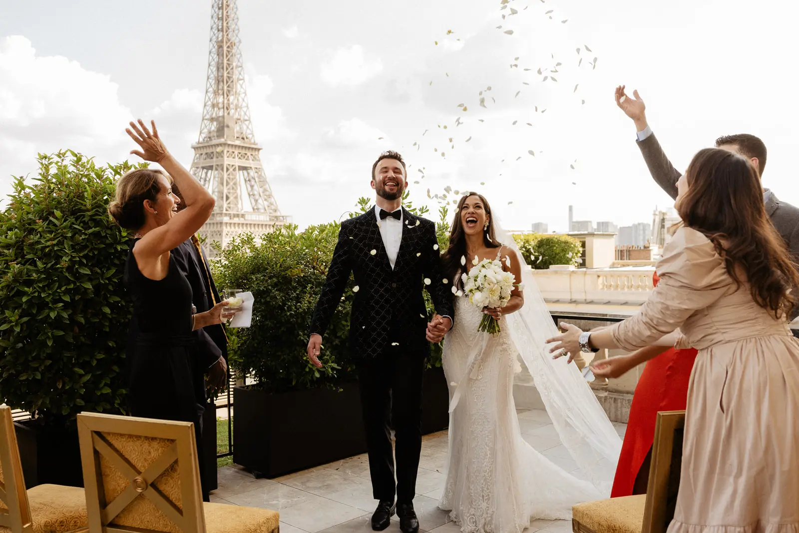 Groom and Bride In Front Of Eiffel Tower Wearing a Beaded Lace Sheath Bridal Gown Called Barrett By Sottero And Midgley