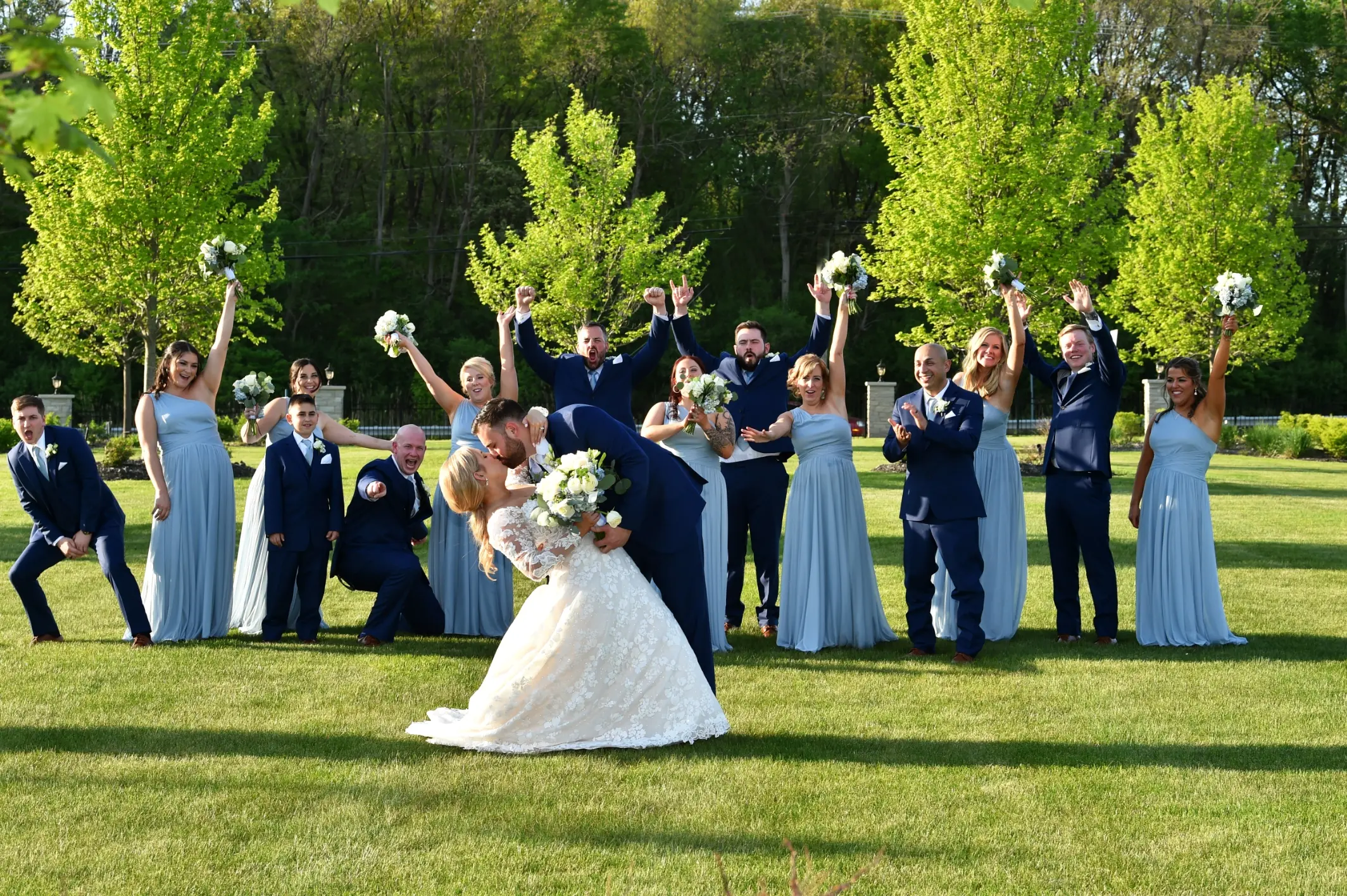 Bride Wearing Long Sleeve Floral Lace Wedding Dress Called Sawyer By Sottero and Midgley With Bridal Party In Background