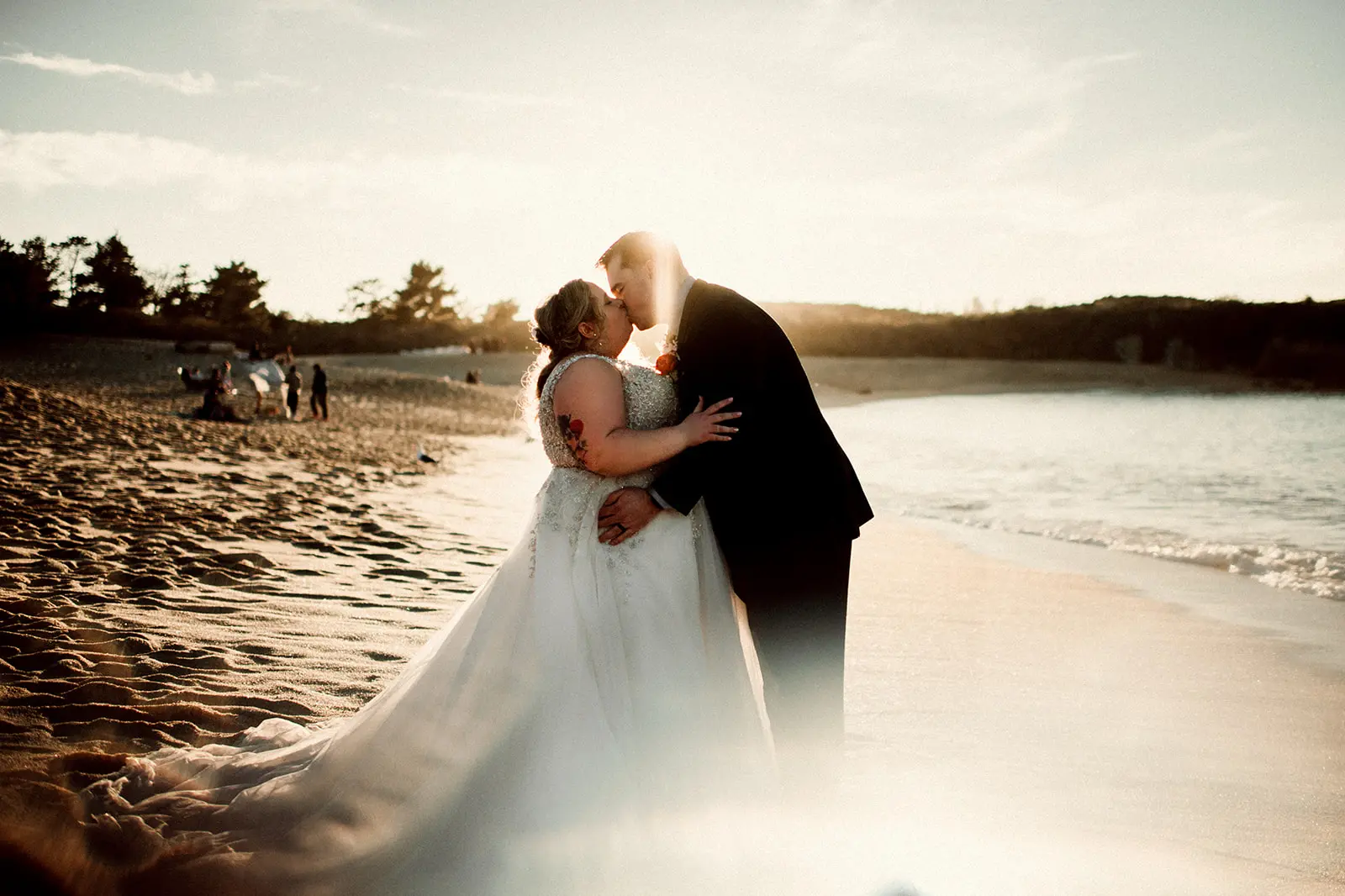 Groom Kissing Bride on Beach in Ball Gown Wedding Dress Named Talia By Maggie Sottero
