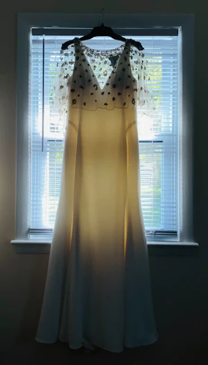 Minimalist Crepe Fit-and-Flare Wedding Dress Called Fernanda by Maggie Sottero Hanging From Window