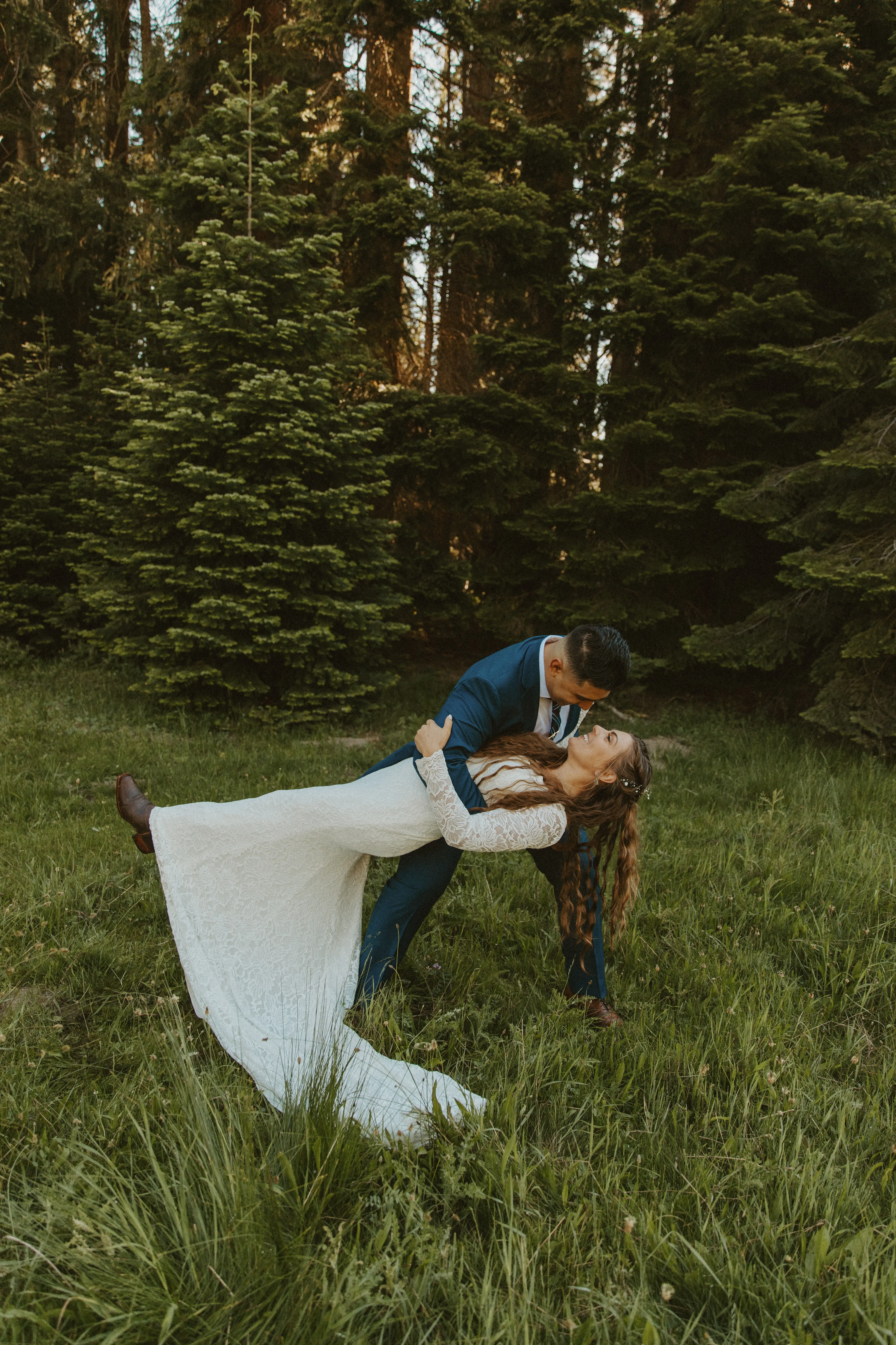 Groom dipping bride in the outdoors. Bride wearing boots with her wedding dress called Tina Dawn.