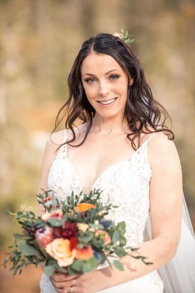 Bride holding an Autumn color bouquet wearing wedding dress called Nikki.