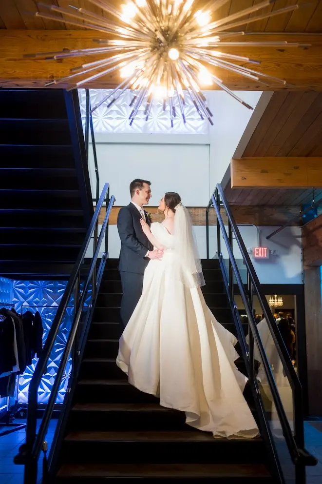 Bride wearing Derrick by Maggie Sottero on the stairs with her husband