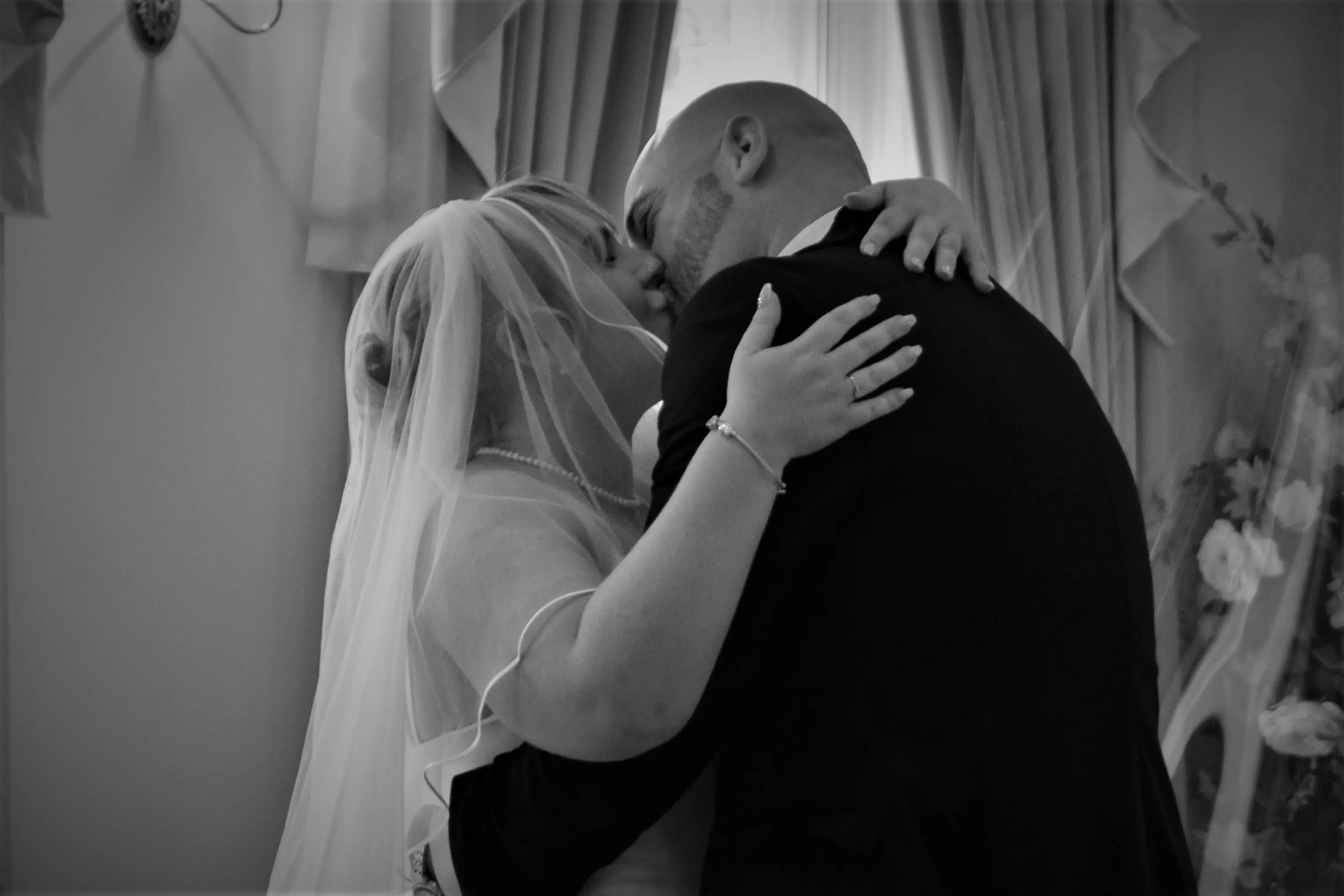Black and white of bride and groom kissing.