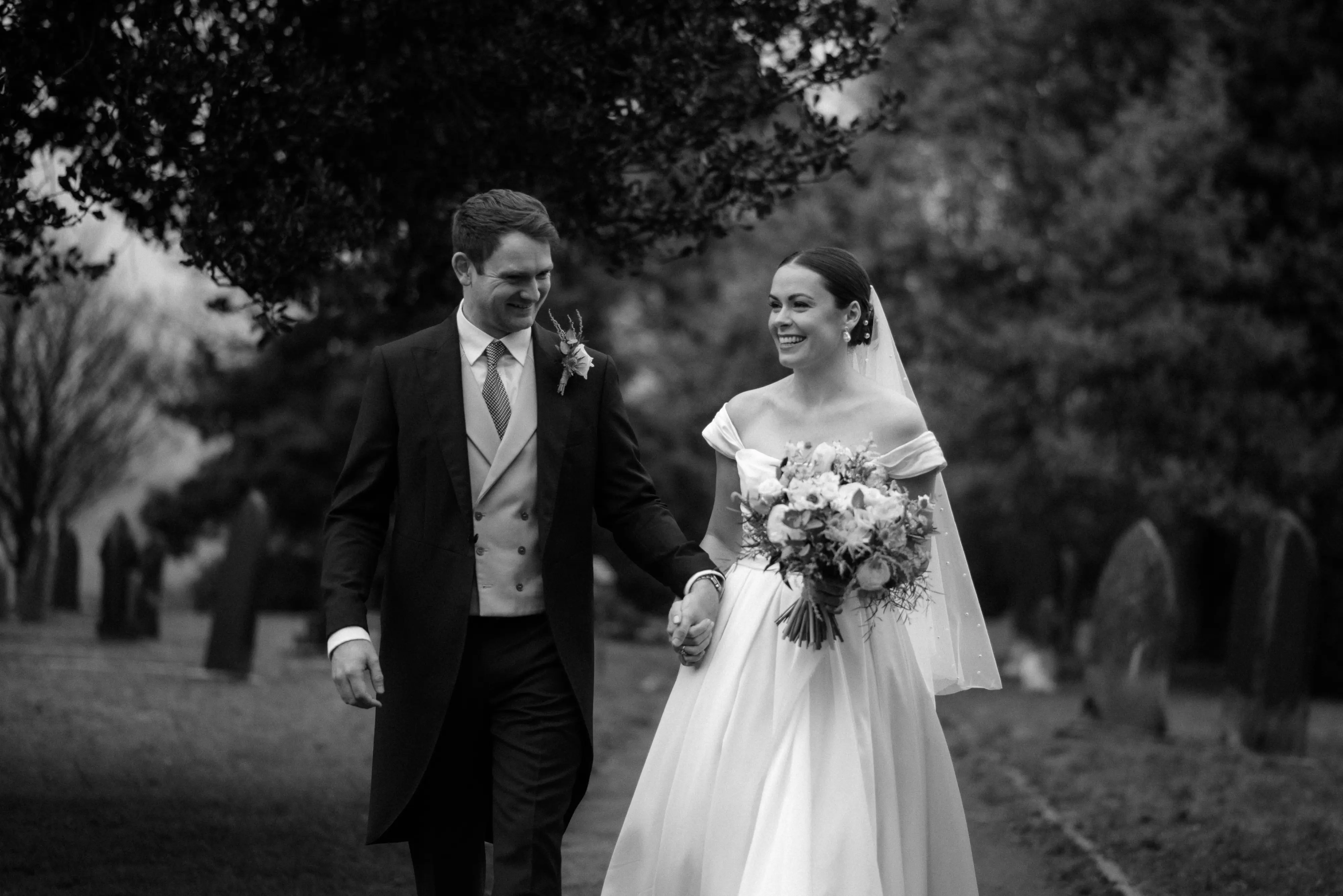 Bride wearing Scarlet wedding dress by Maggie Sottero holding hands with her husband