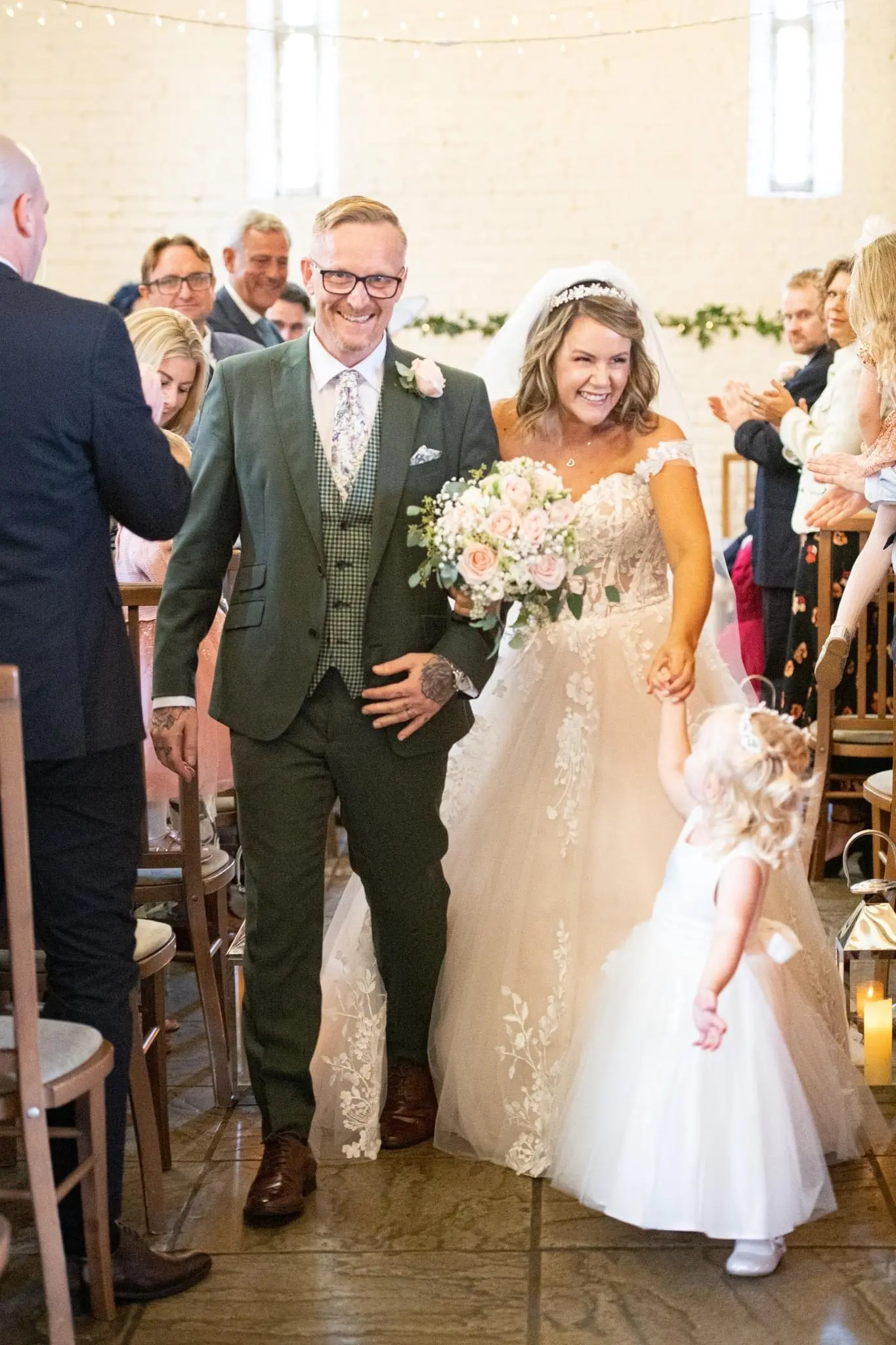 Bride wearing Harlem wedding dress by Maggie Sottero walking down the aisle with husband and daughter