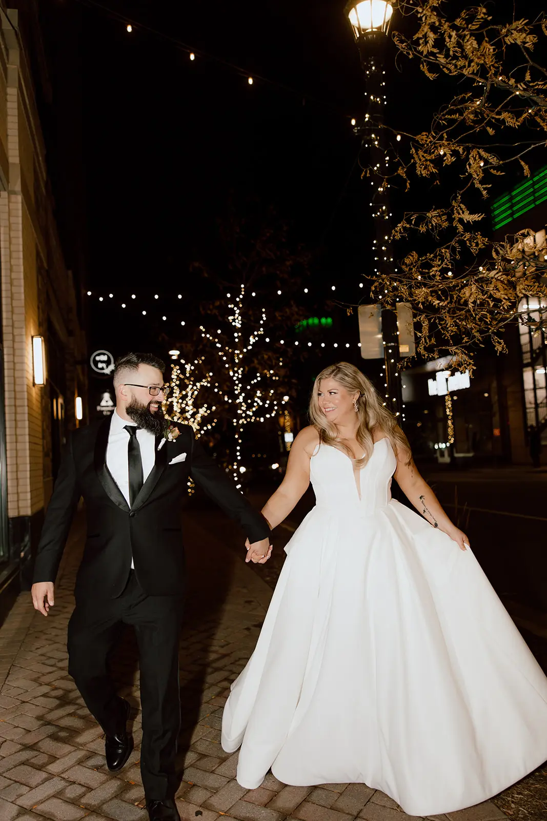 Bride wearing Derrick by Maggie Sottero walking down the street with her husband