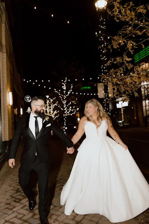 Bride wearing Derrick by Maggie Sottero walking down the street with her husband