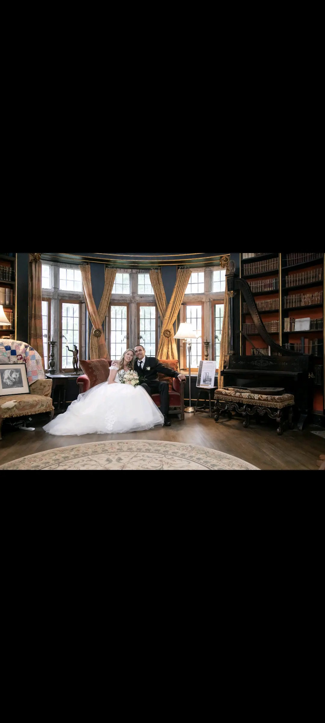 Bride wearing Harlem wedding dress by Maggie Sottero sitting on a couch with her husband